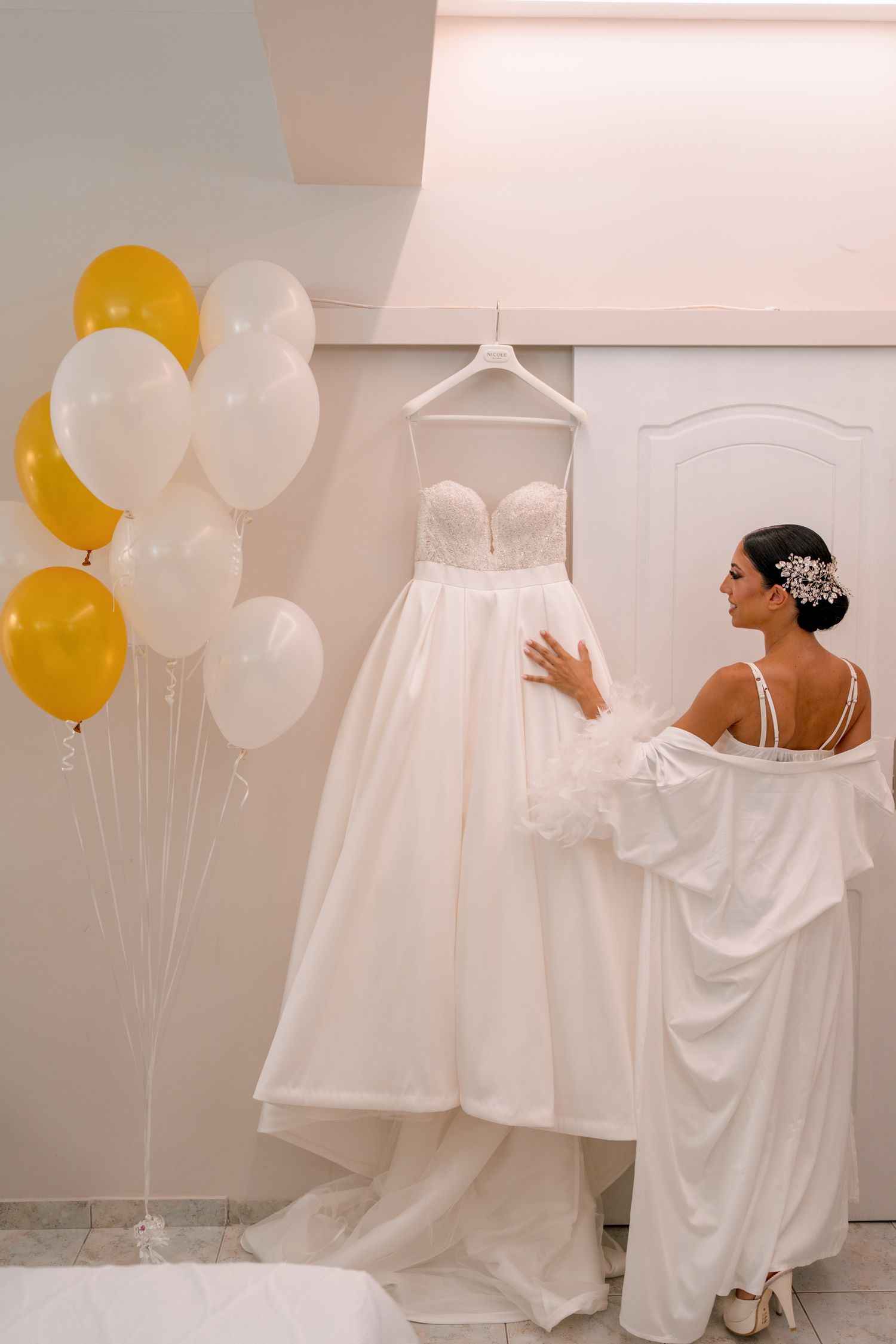 Wedding dresses and balloons decorating a bright white room.