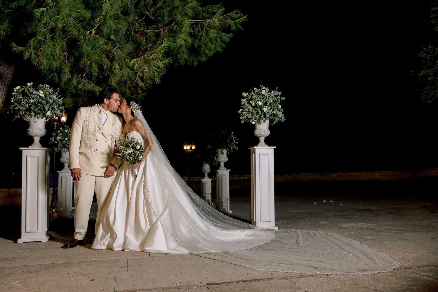 Romantic nighttime wedding ceremony setup with white columns and floral decorations.