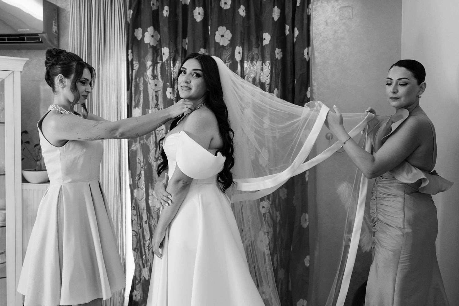Wedding preparation scene with bridesmaids helping with a white dress.