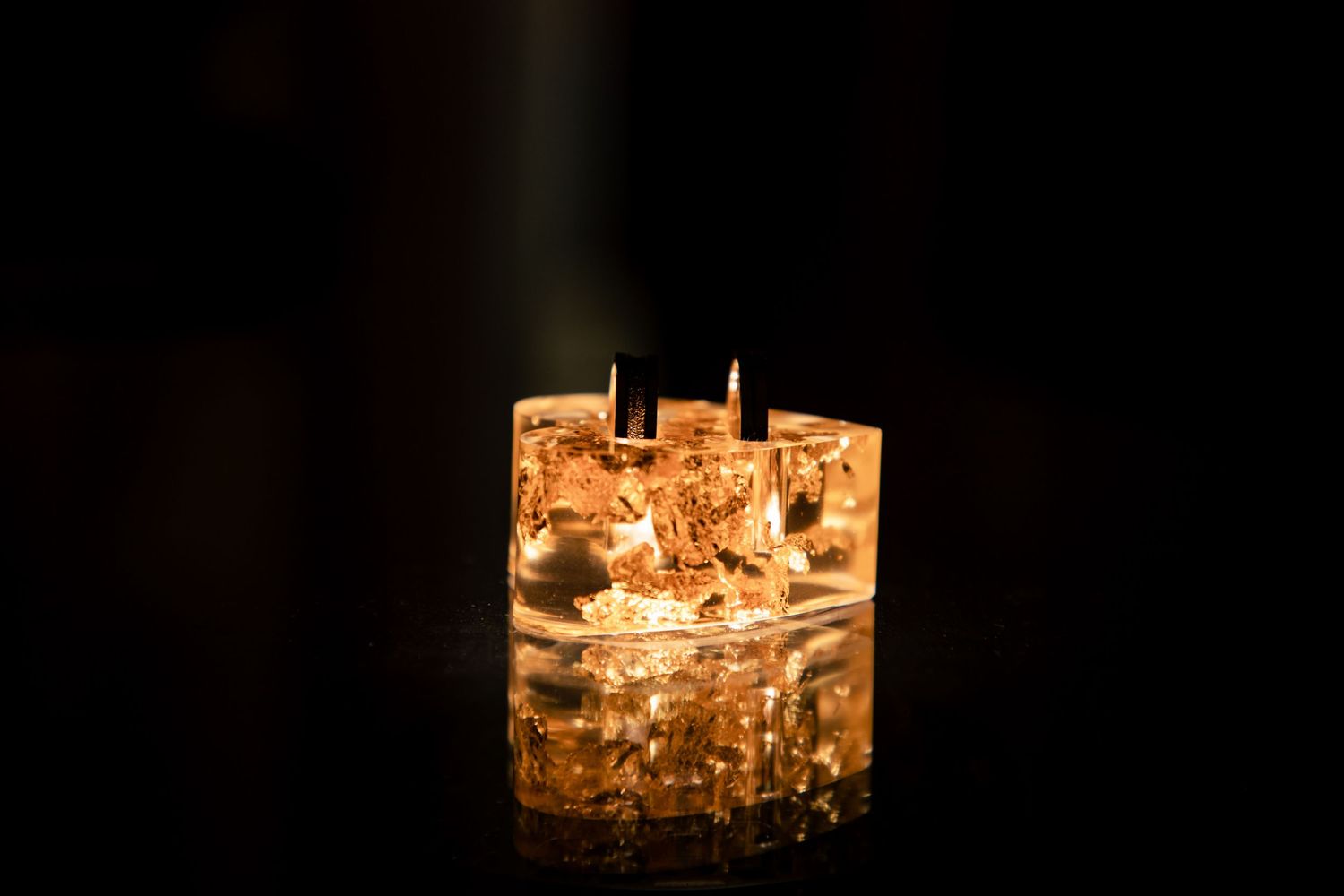 Row of glowing amber tea lights casting soft illumination in a dark setting.