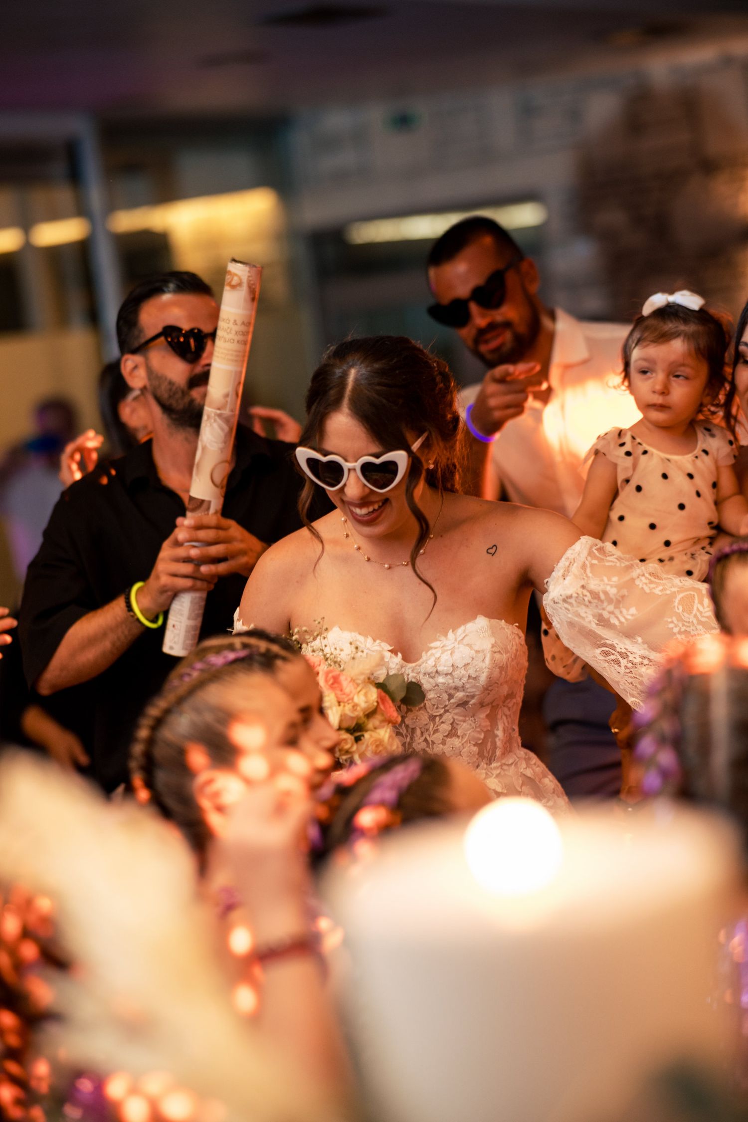 Guests celebrate at a wedding reception with heart-shaped sunglasses and elegant decor.