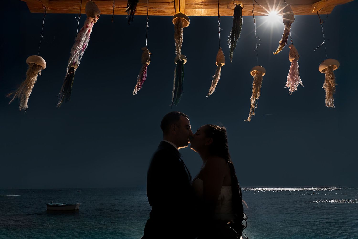 Silhouettes of a couple against a dramatic evening sky with hanging decorations.