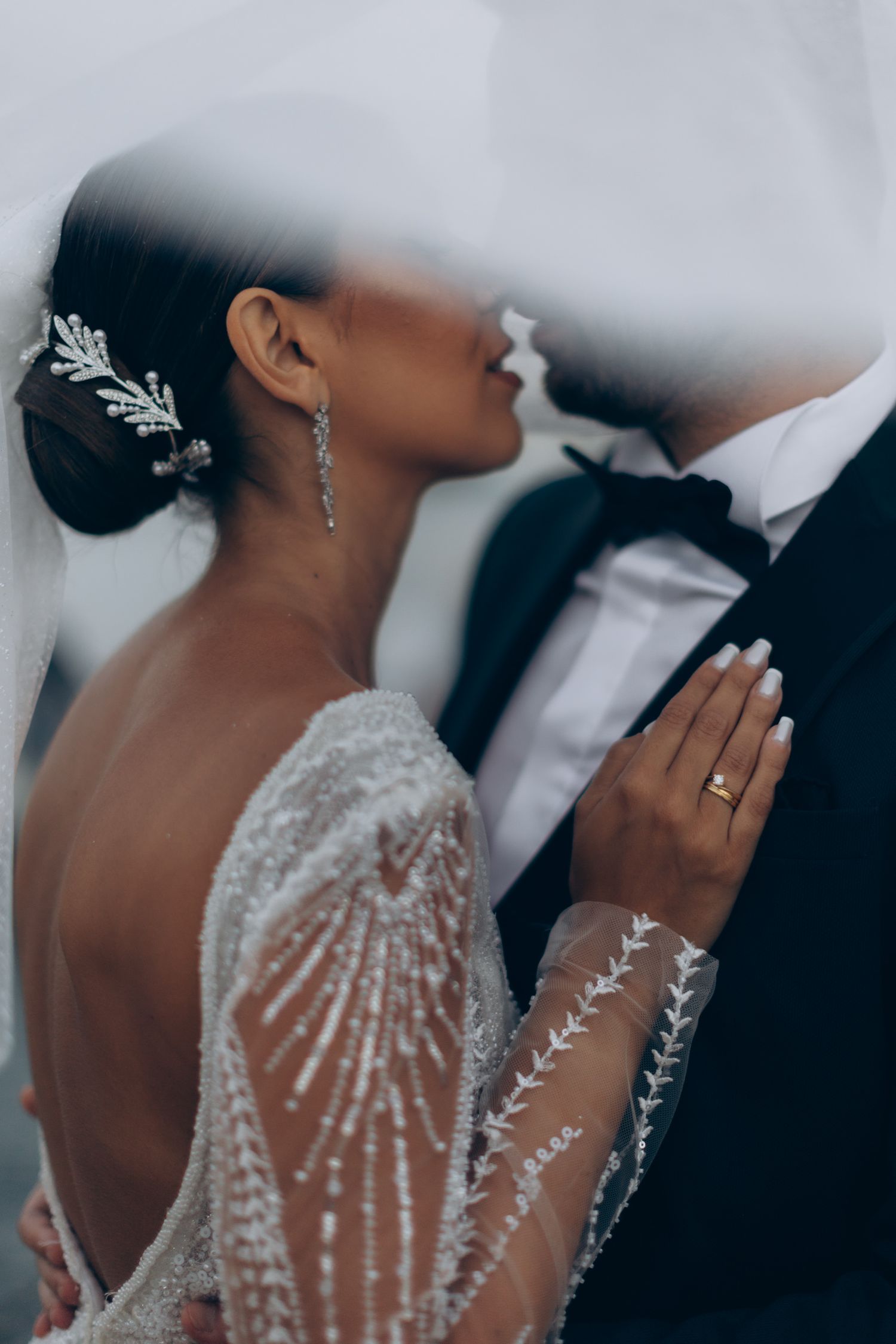 Close-up wedding photo showing intricate lace details and elegant jewelry against a soft background.