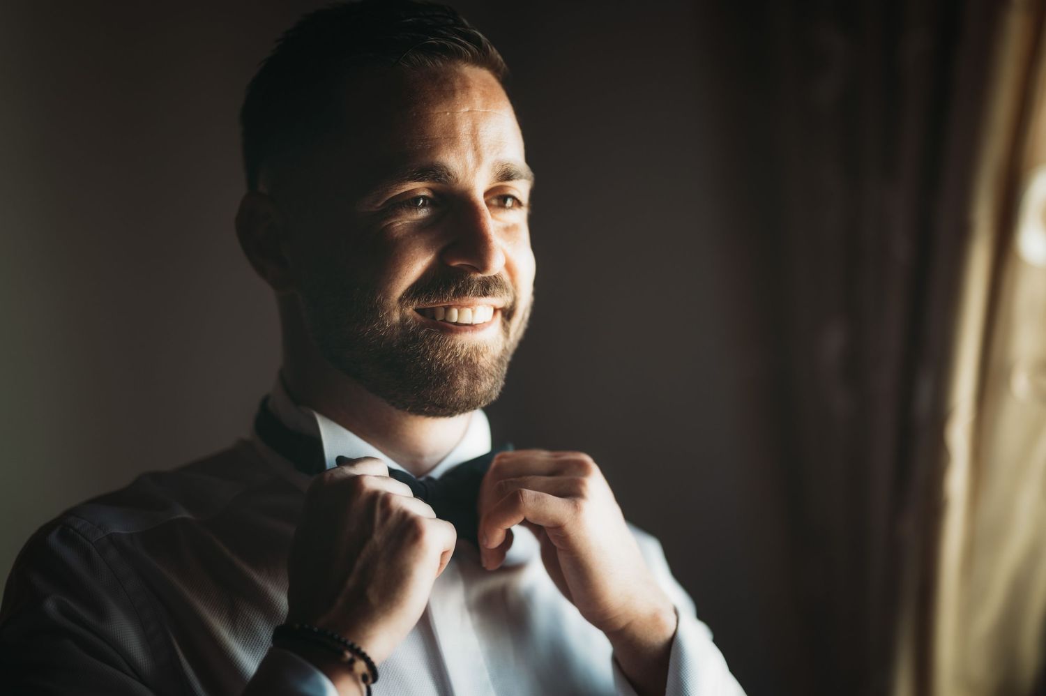 Candid moments captured during wedding preparation in natural window light.