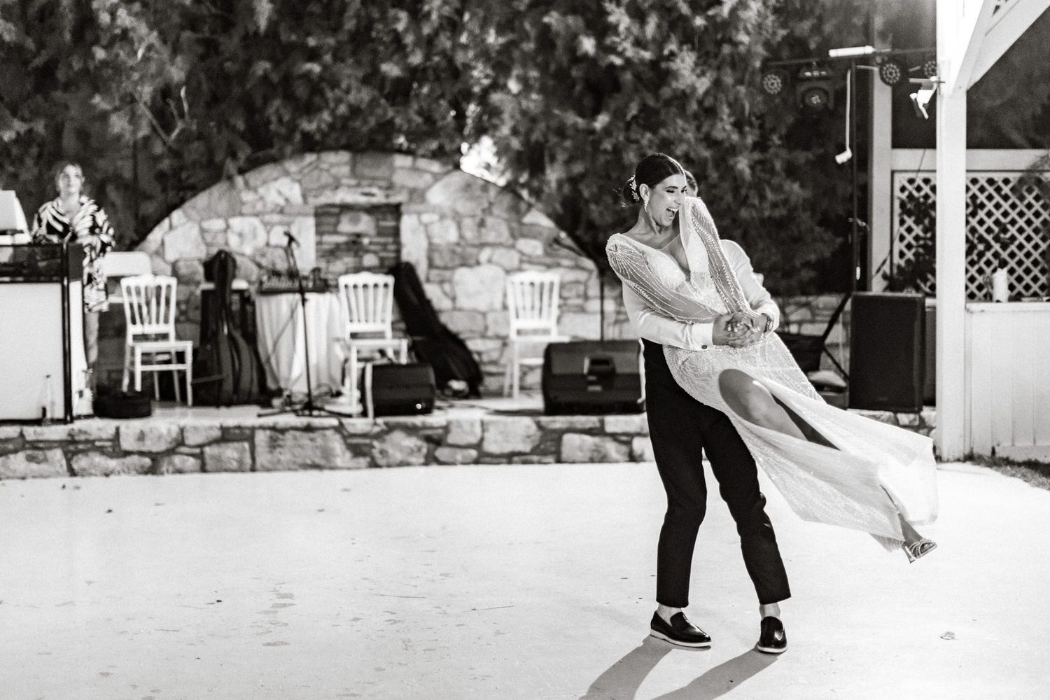 Wedding couple performing a romantic dip during their dance under string lights.