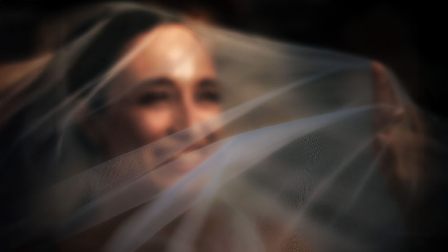 Artistic black and white wedding veil detail shot with dramatic lighting effects.