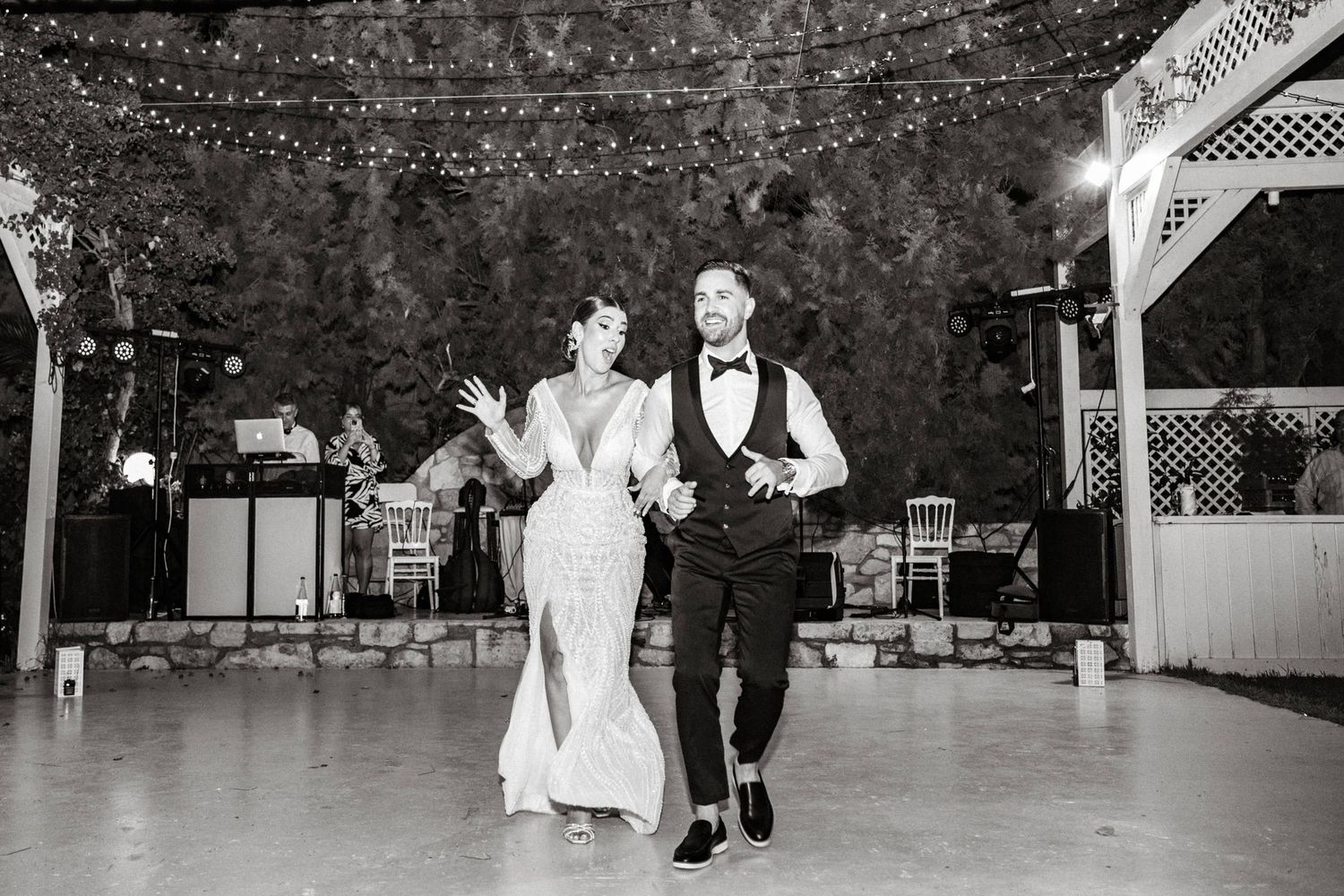 Outdoor wedding reception dance floor with string lights and white trellis.