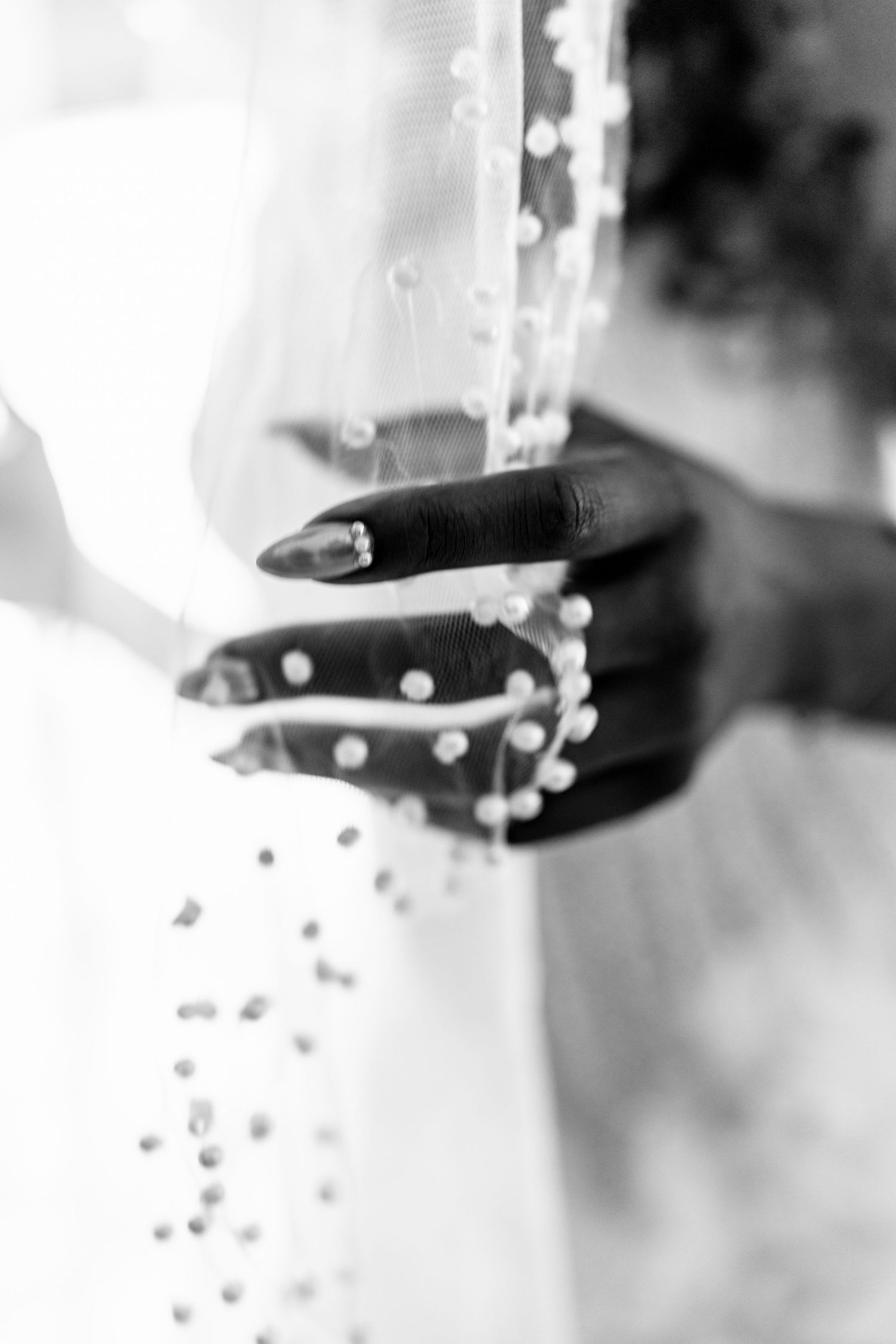 Artistic black and white detail shot of pearls and beading on bridal accessories.