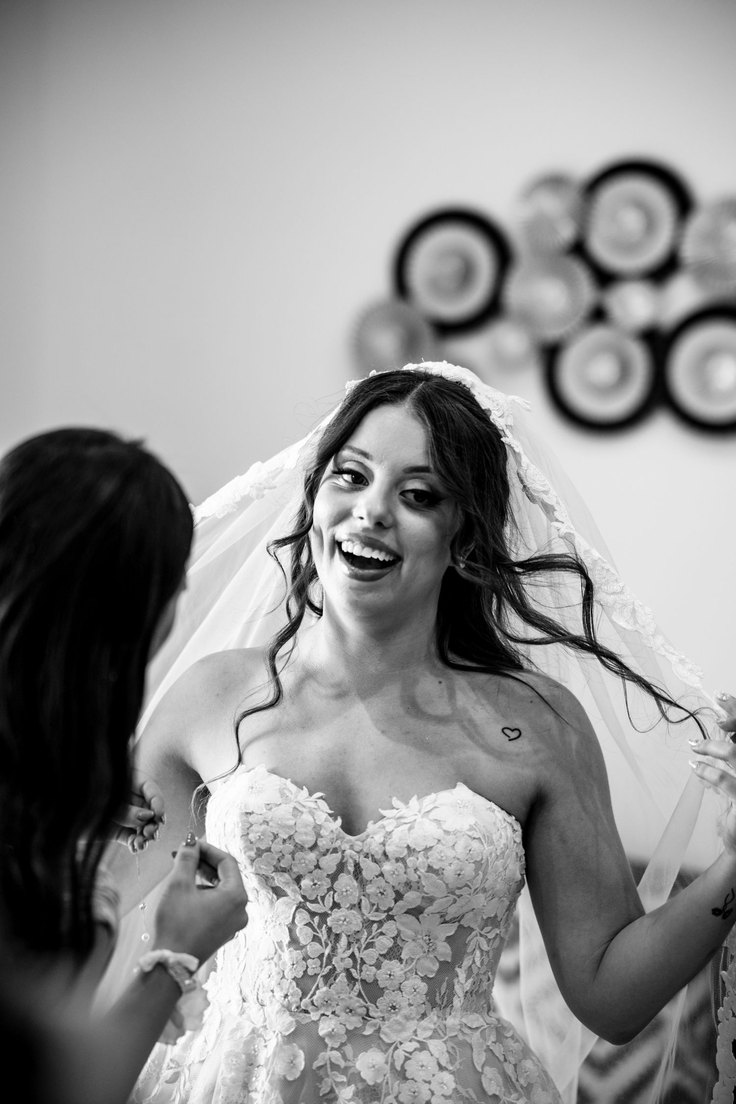 A joyful black and white moment captured during wedding preparations with decorative wall art.