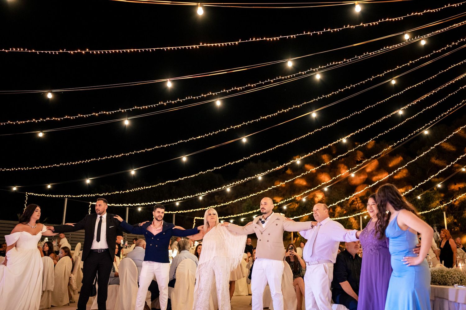 String lights create a canopy over an outdoor wedding reception dance floor.