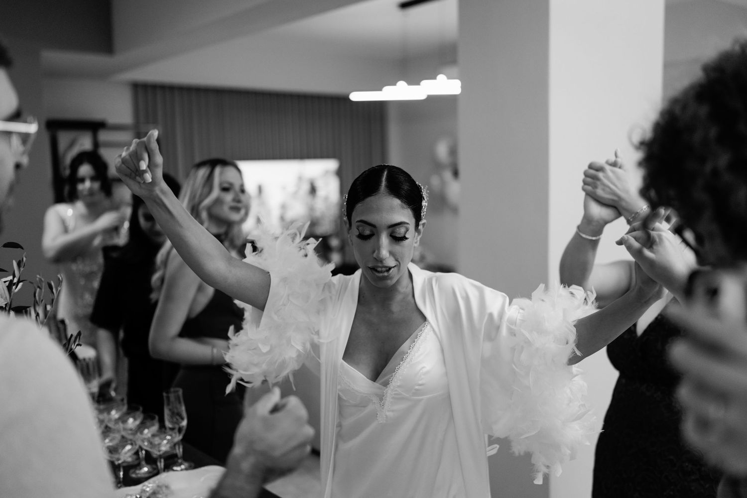 Black and white photo of wedding reception guests dancing with arms raised.