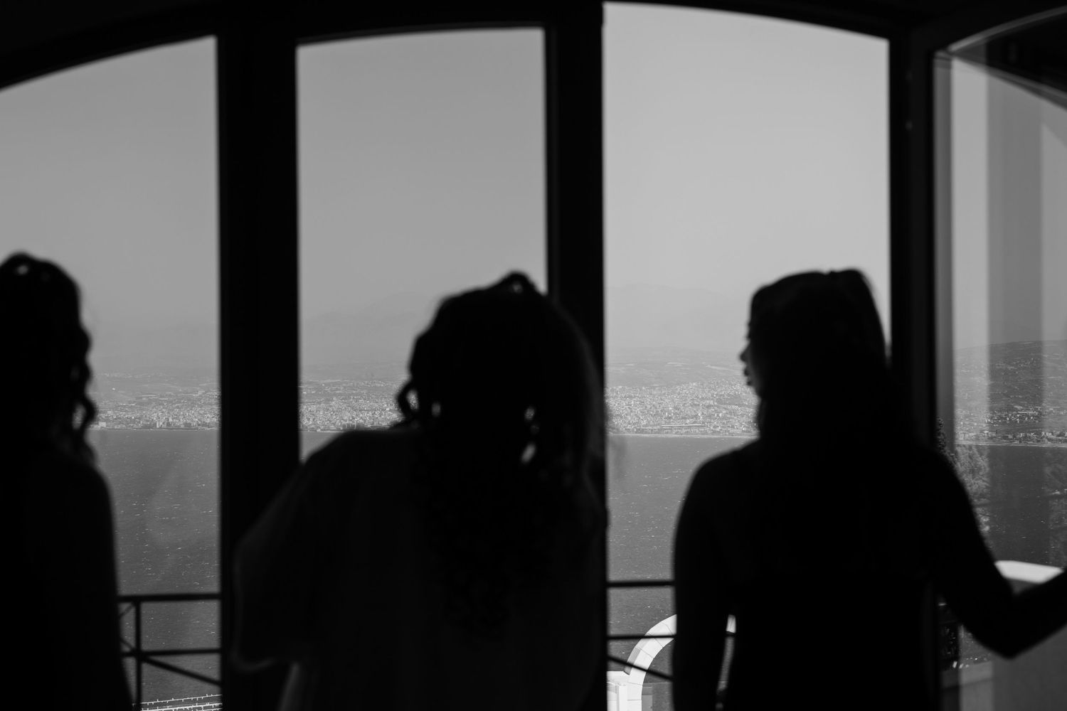 Silhouettes of people against large windows in a modern building.