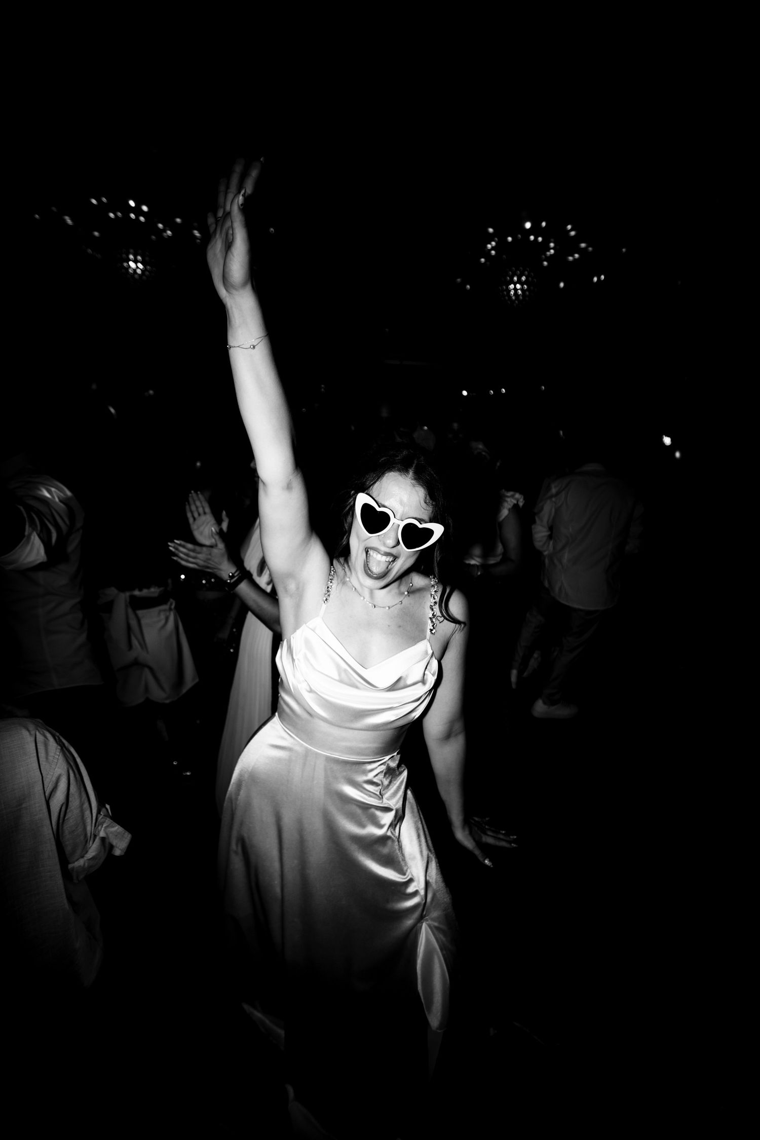 Silhouettes of people dancing with hands raised in a dimly lit nightclub atmosphere.