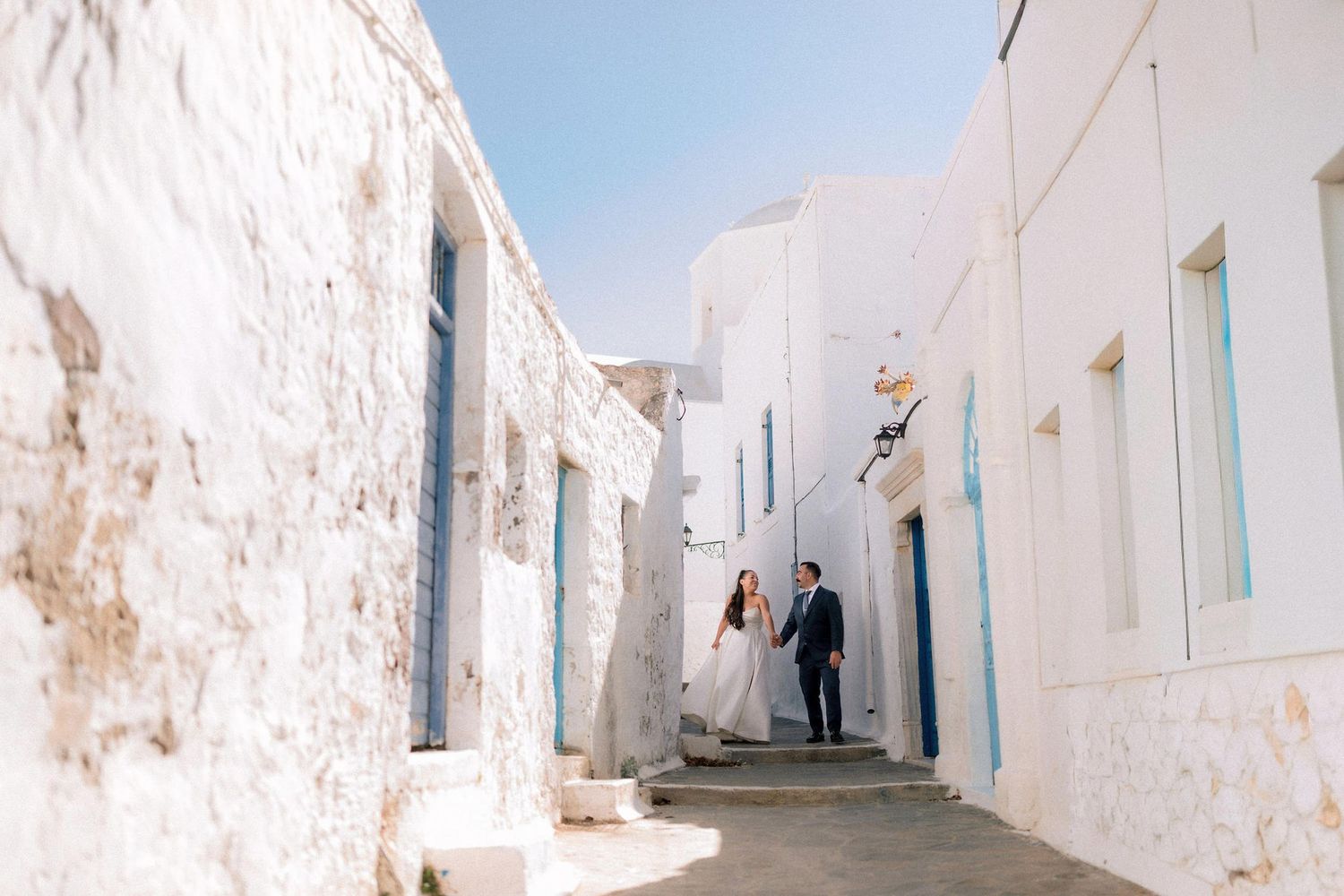 Wedding couple walking through white Mediterranean village alleyways.