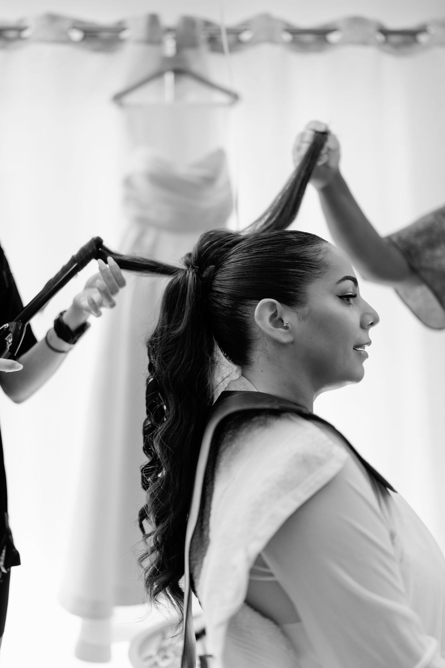Black and white photo showing hair styling preparation in a bright room.