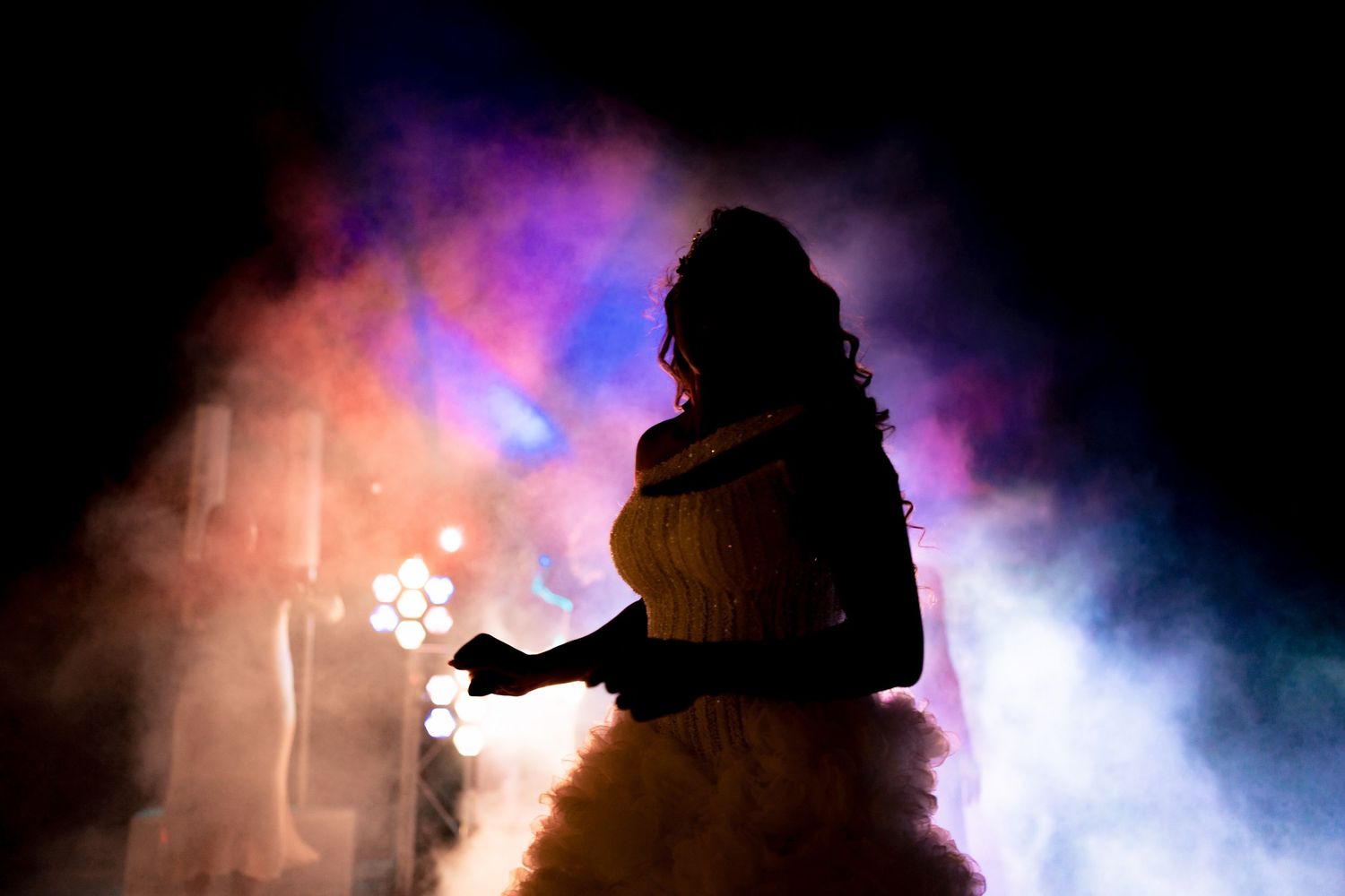 A silhouetted figure dances in dramatic purple and blue smoke effects.