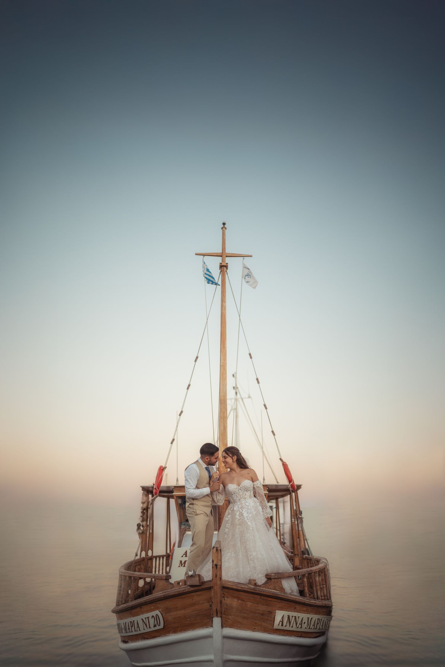 A wooden boat floats serenely on calm waters during golden hour with wedding party aboard.