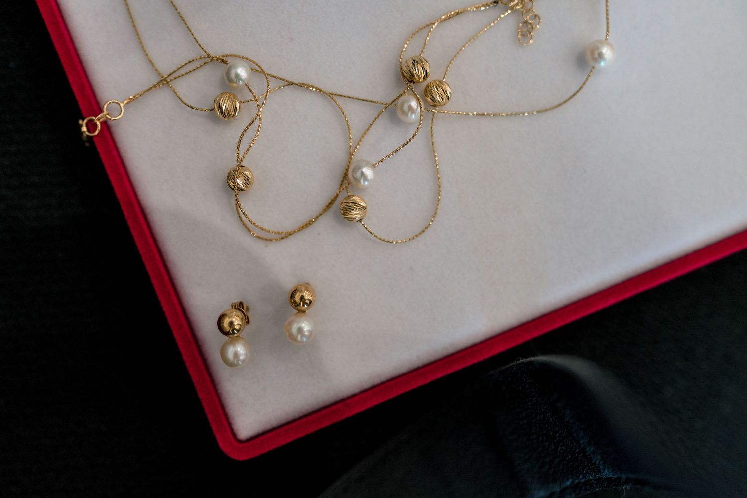 Delicate gold jewelry with pearls displayed in a red box.