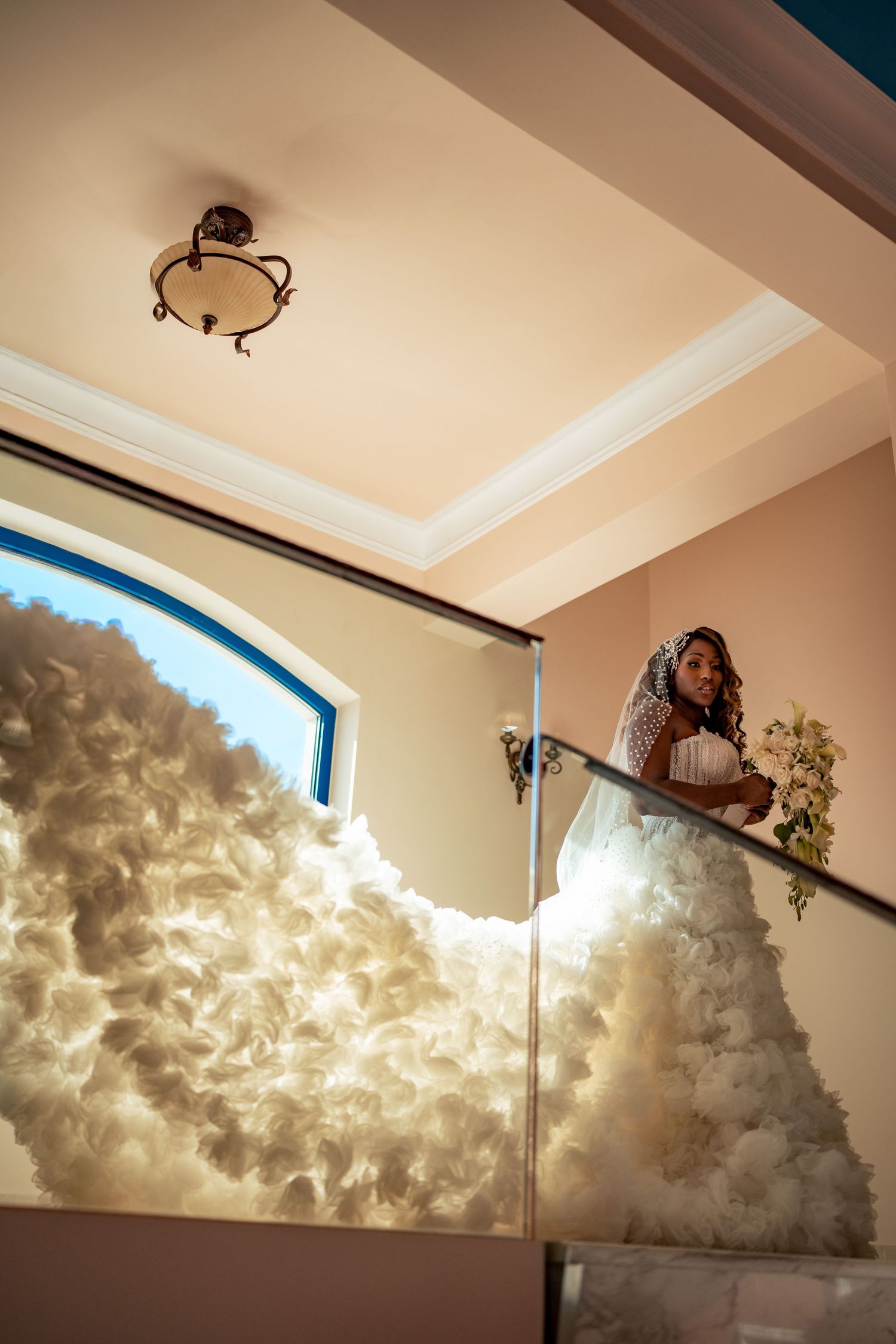 Modern wedding venue interior with dramatic cloud-like ceiling installation and arched windows.