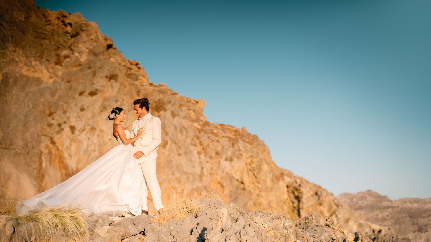 A scenic desert wedding photoshoot with dramatic rock formations and blue sky.