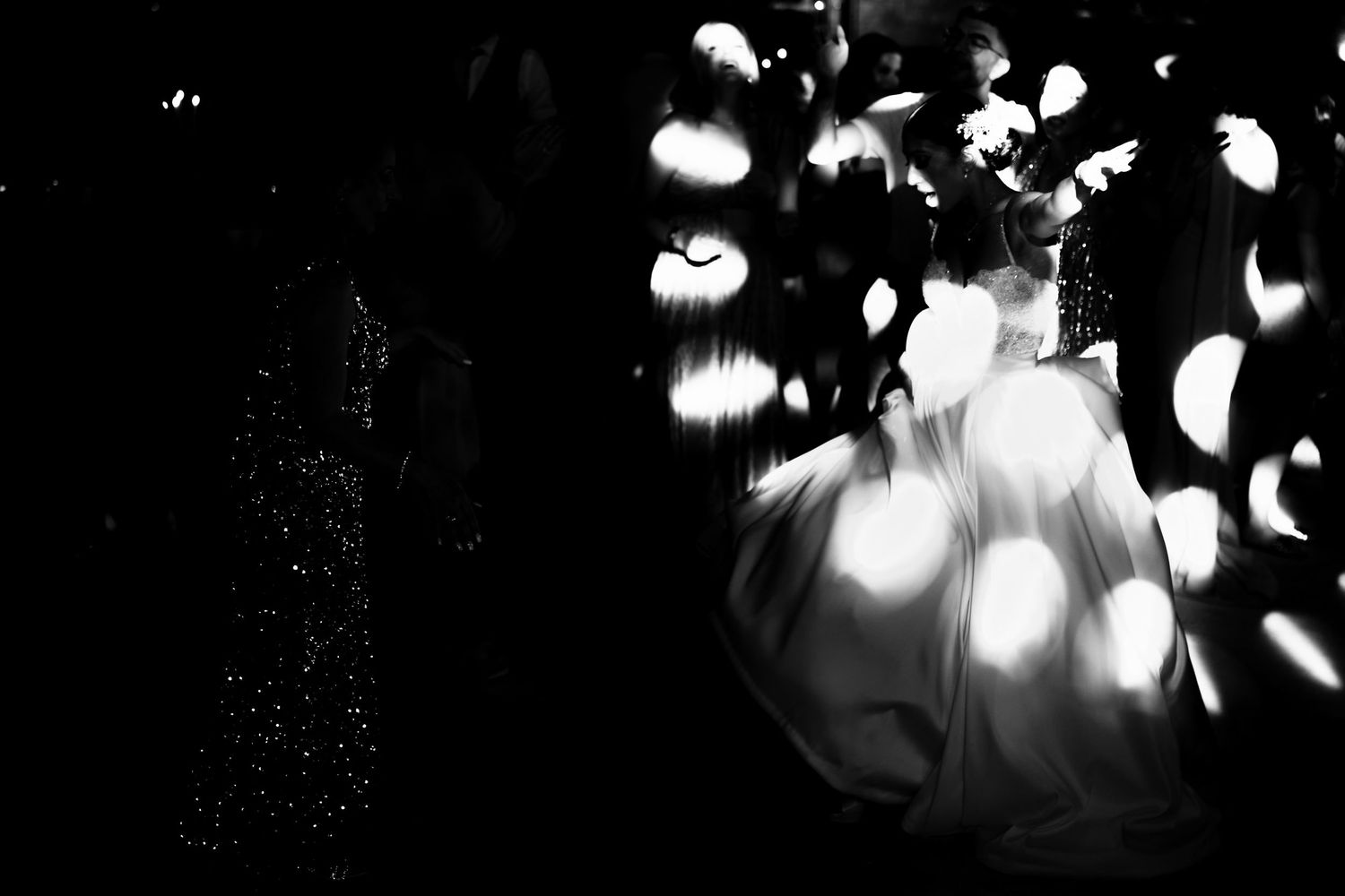 Ethereal black and white wedding photo with dramatic lighting and floating bokeh effects.