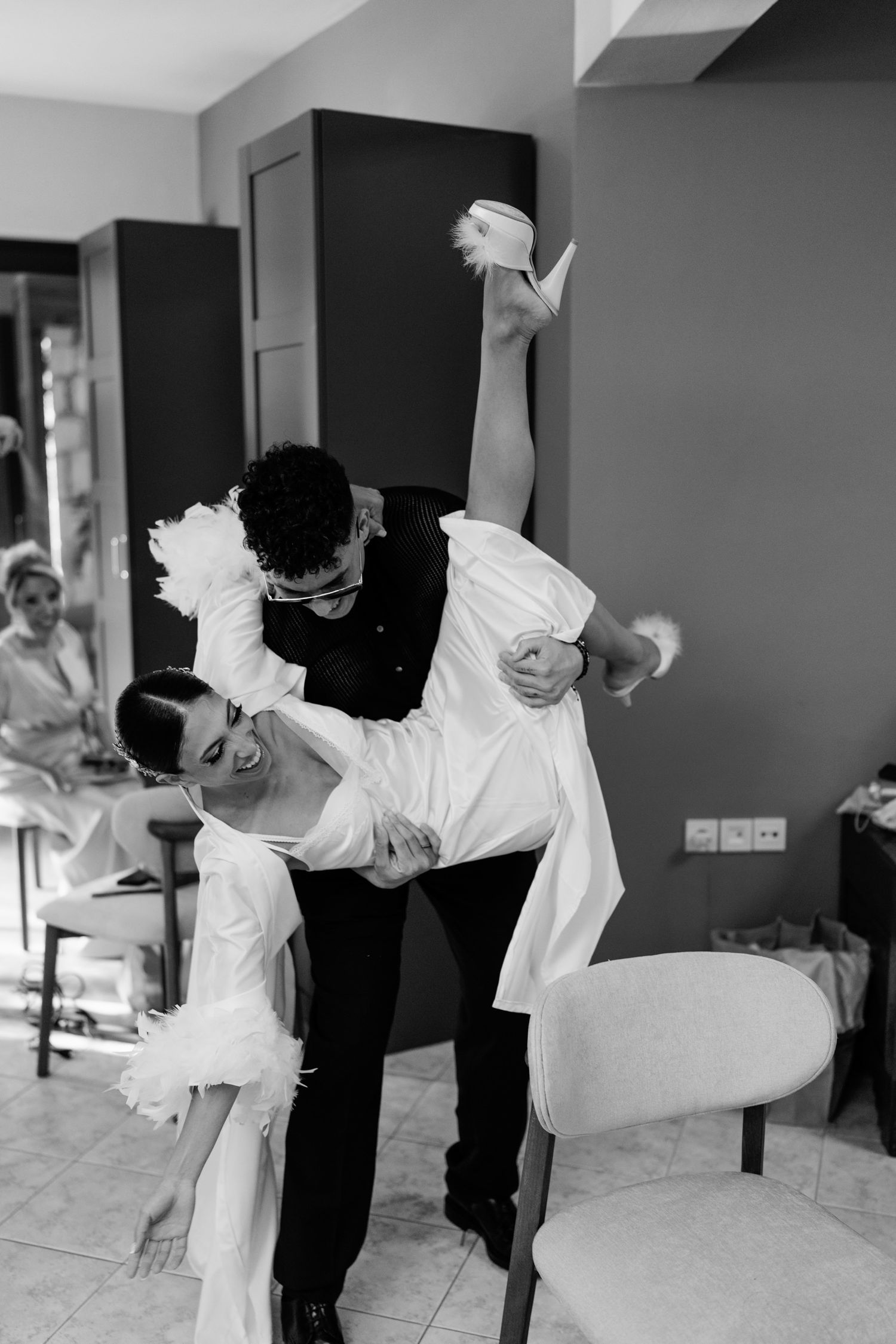 Wedding party members dance energetically in formal attire during celebration.