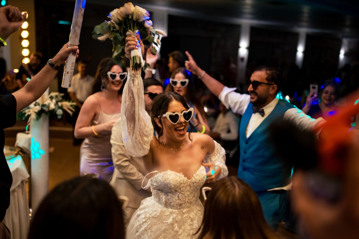 Wedding celebration with party guests dancing under dramatic lighting.
