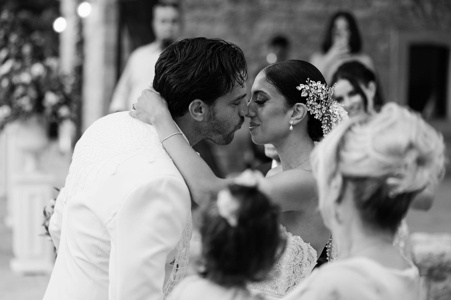 Romantic wedding couple sharing a tender kiss during their outdoor ceremony celebration.