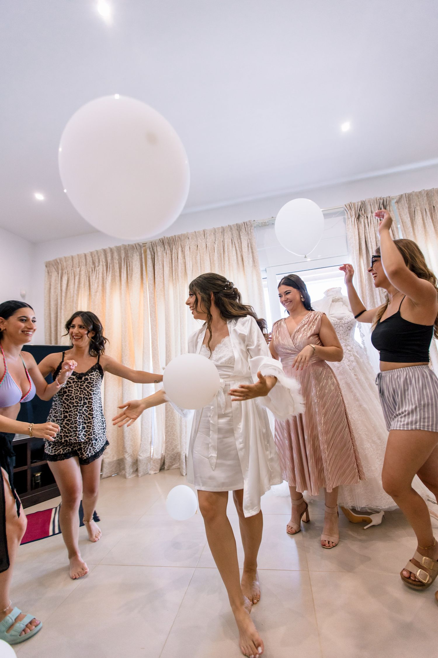 Group playing with white balloons in a bright room during a celebration.