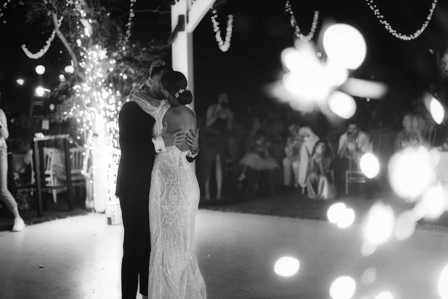 Black and white photo of wedding reception with string lights creating a magical atmosphere.