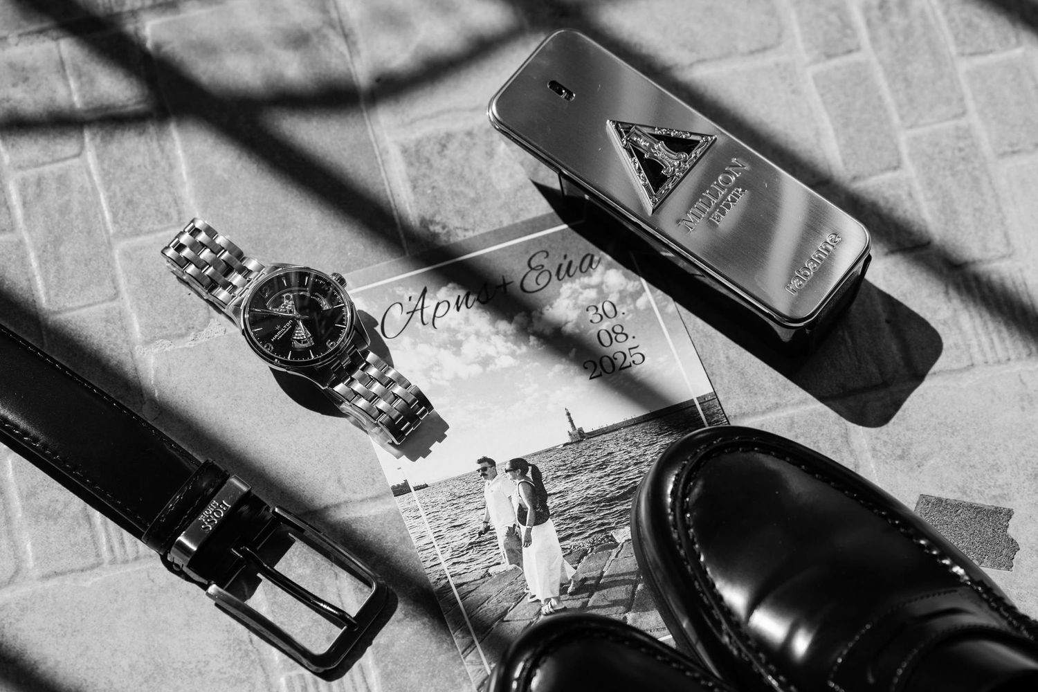 Flat lay of men's accessories including watch, belt, and dress shoes.