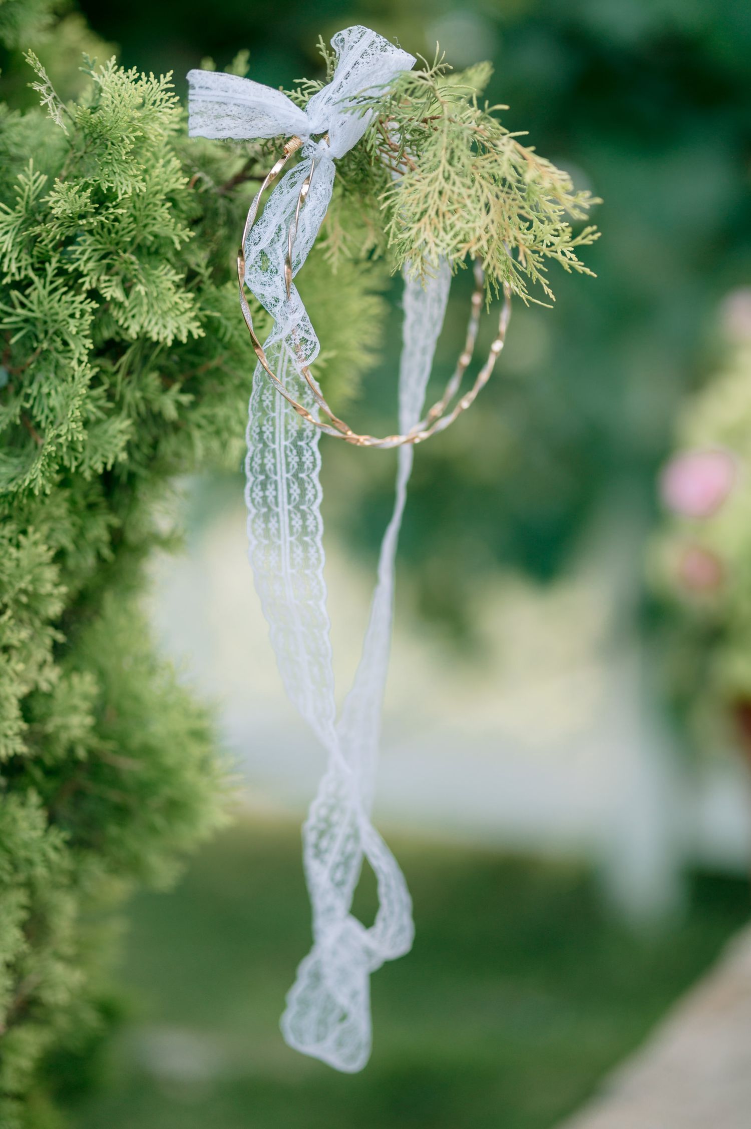 Delicate white lace ribbons tied to green foliage create romantic wedding decor.