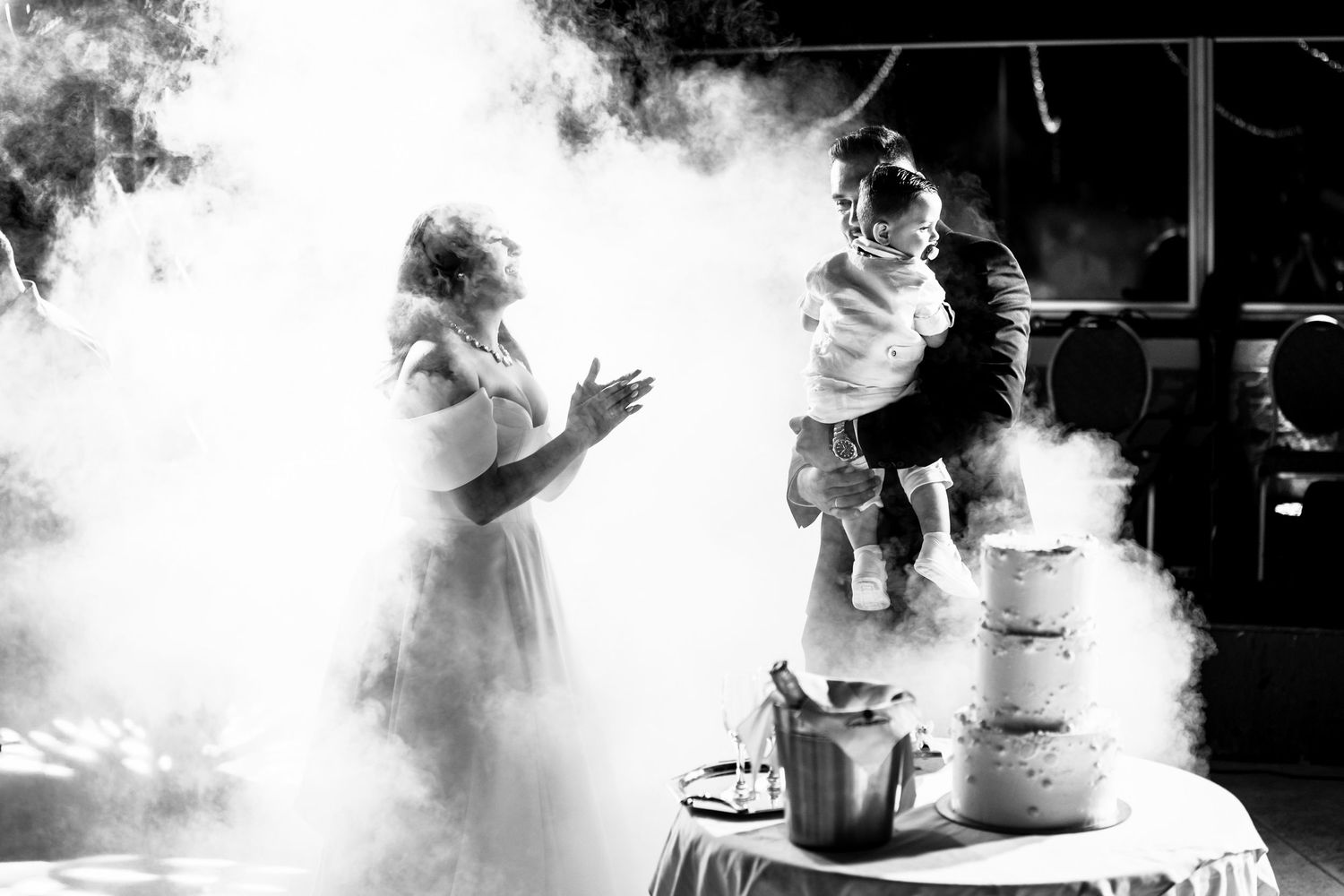 Atmospheric smoke effect creates dramatic silhouettes during wedding dance moments.