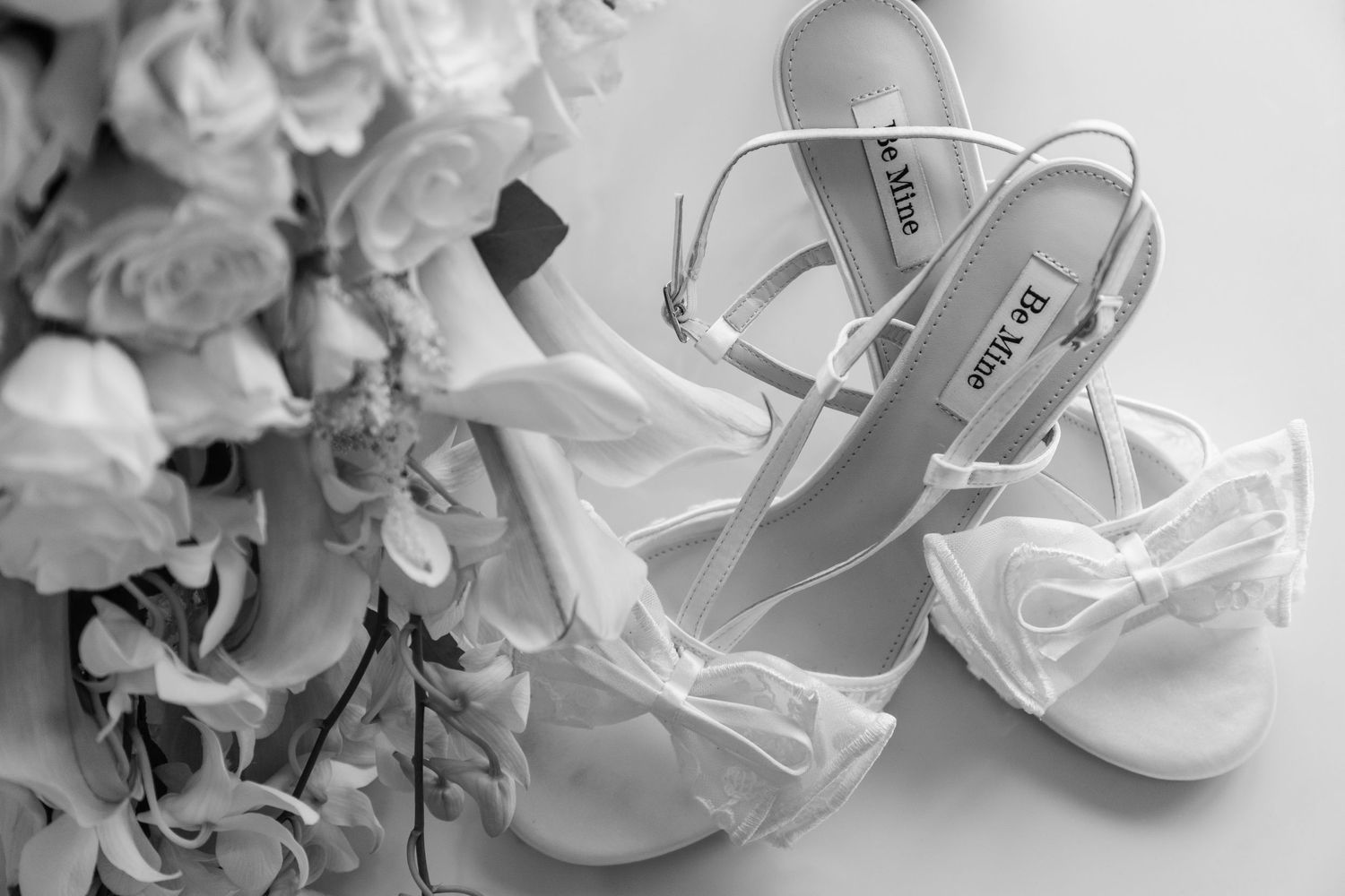 Elegant white bridal shoes and delicate floral arrangements displayed on a light surface.