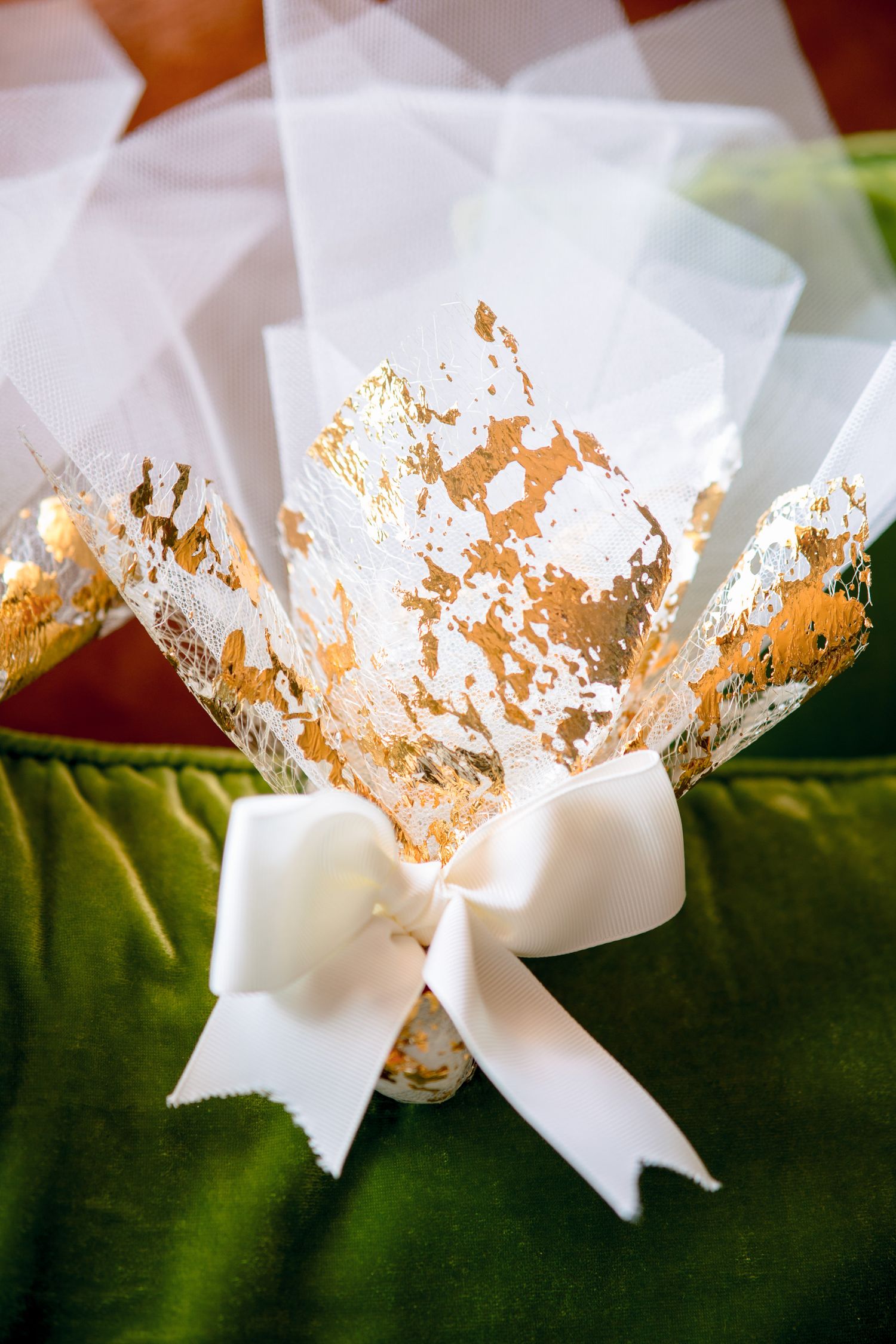 White decorative bow with gold leaf accents on green fabric.