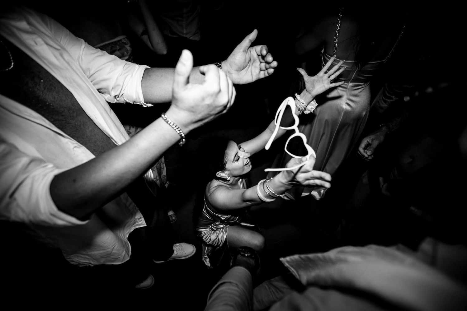 Black and white photo of party guests dancing with sunglasses at night.