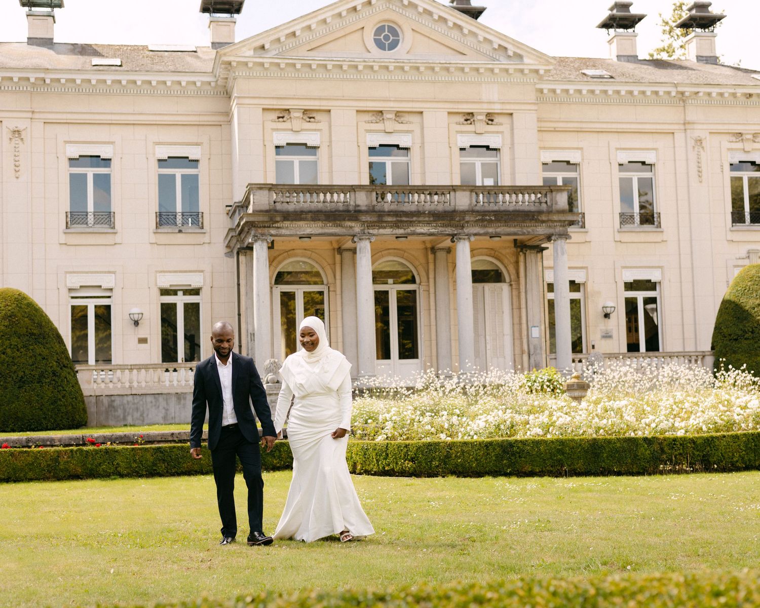 A grand white mansion with classical architecture serves as a backdrop for formal event photography.
