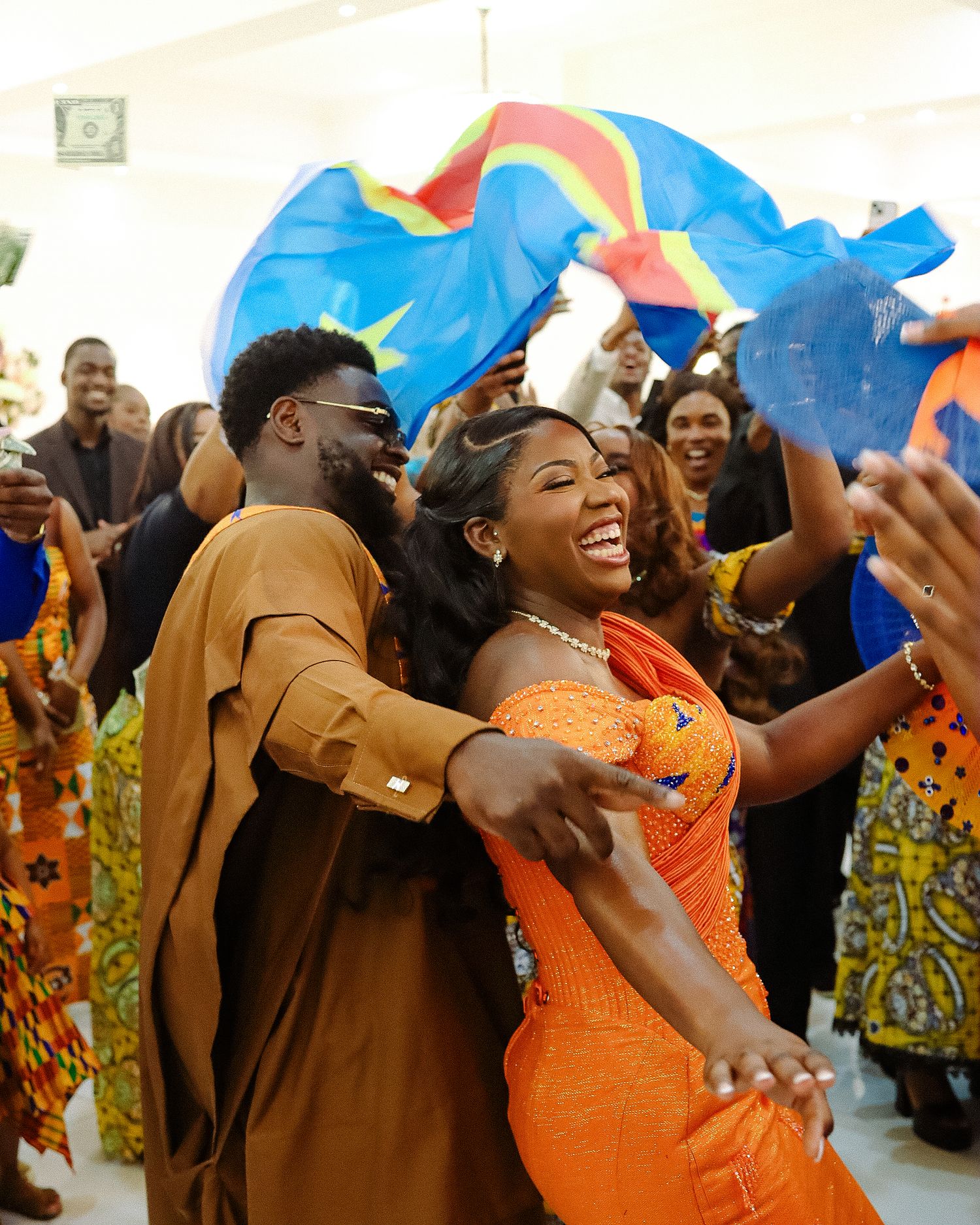 A joyous celebration features wedding guests in colorful attire dancing and celebrating enthusiastically.