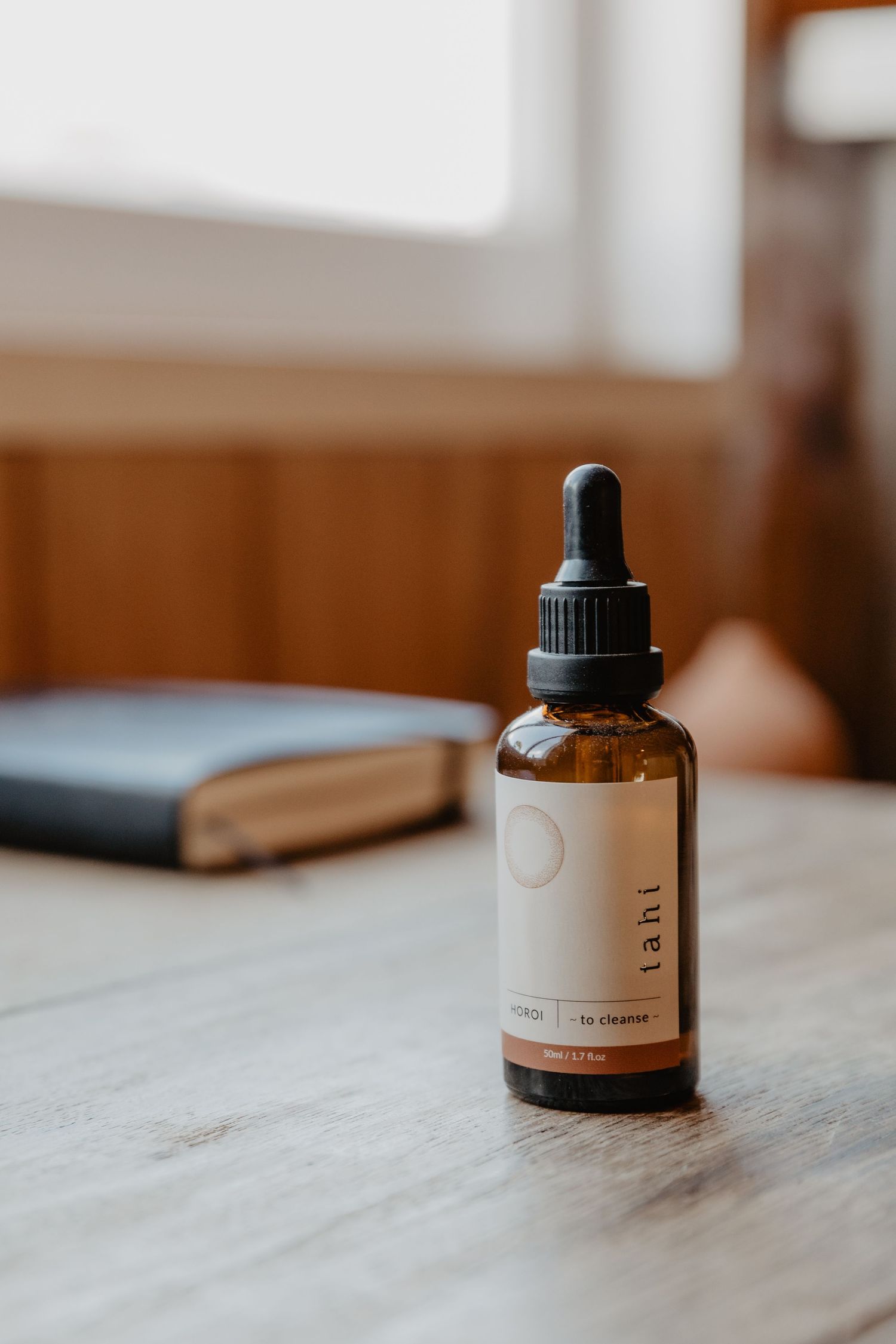 Minimalist product bottles with dropper caps arranged on a light wooden surface.