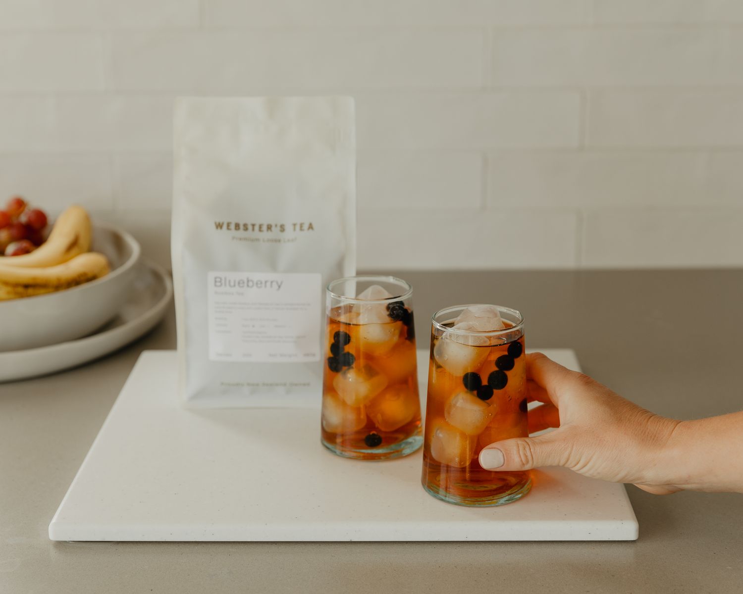 Minimalist tea service setup with glass jars on white marble countertop.