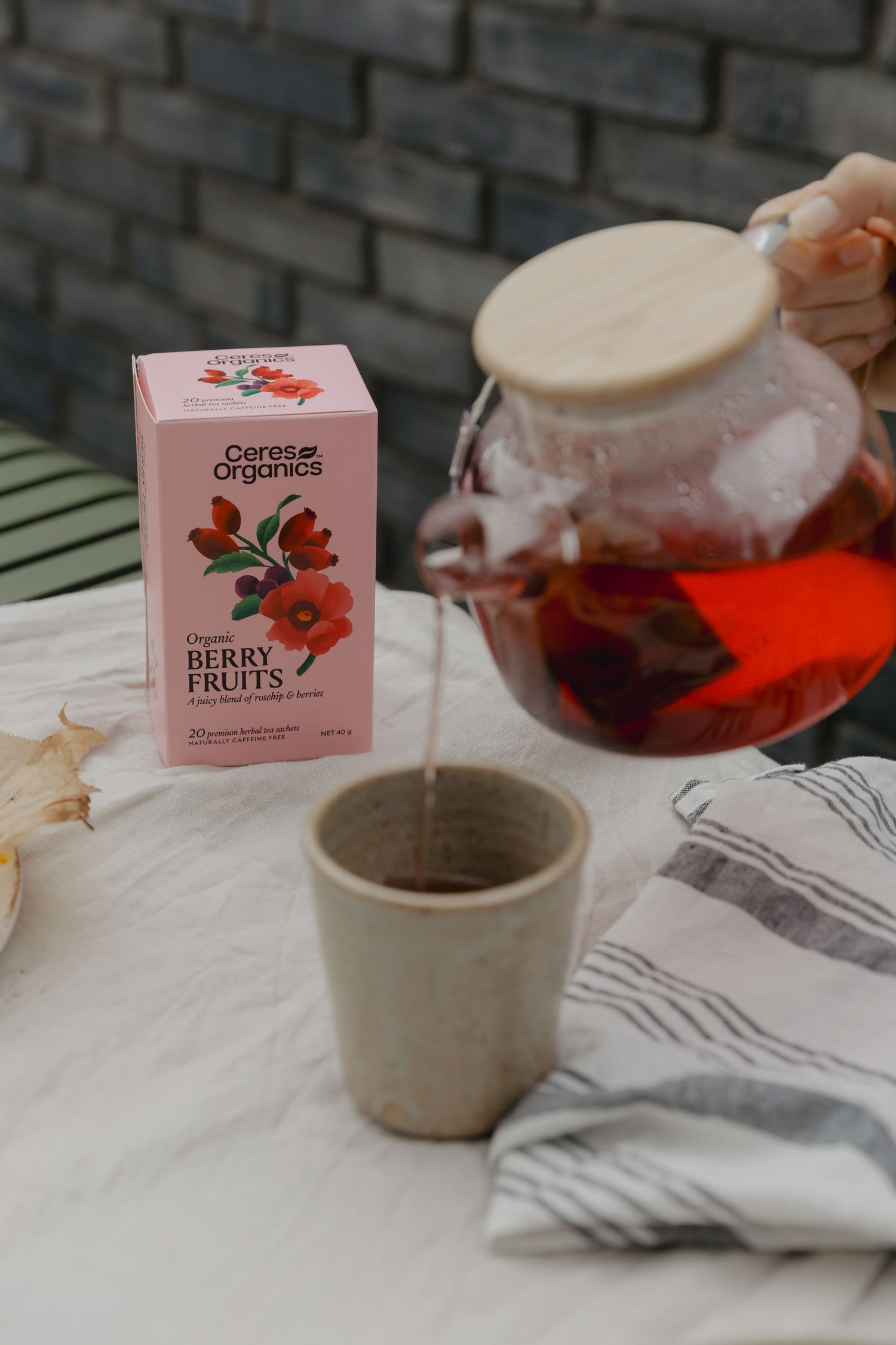 Tea boxes and ceramic cups arranged on a white tablecloth with fruit tea being served.