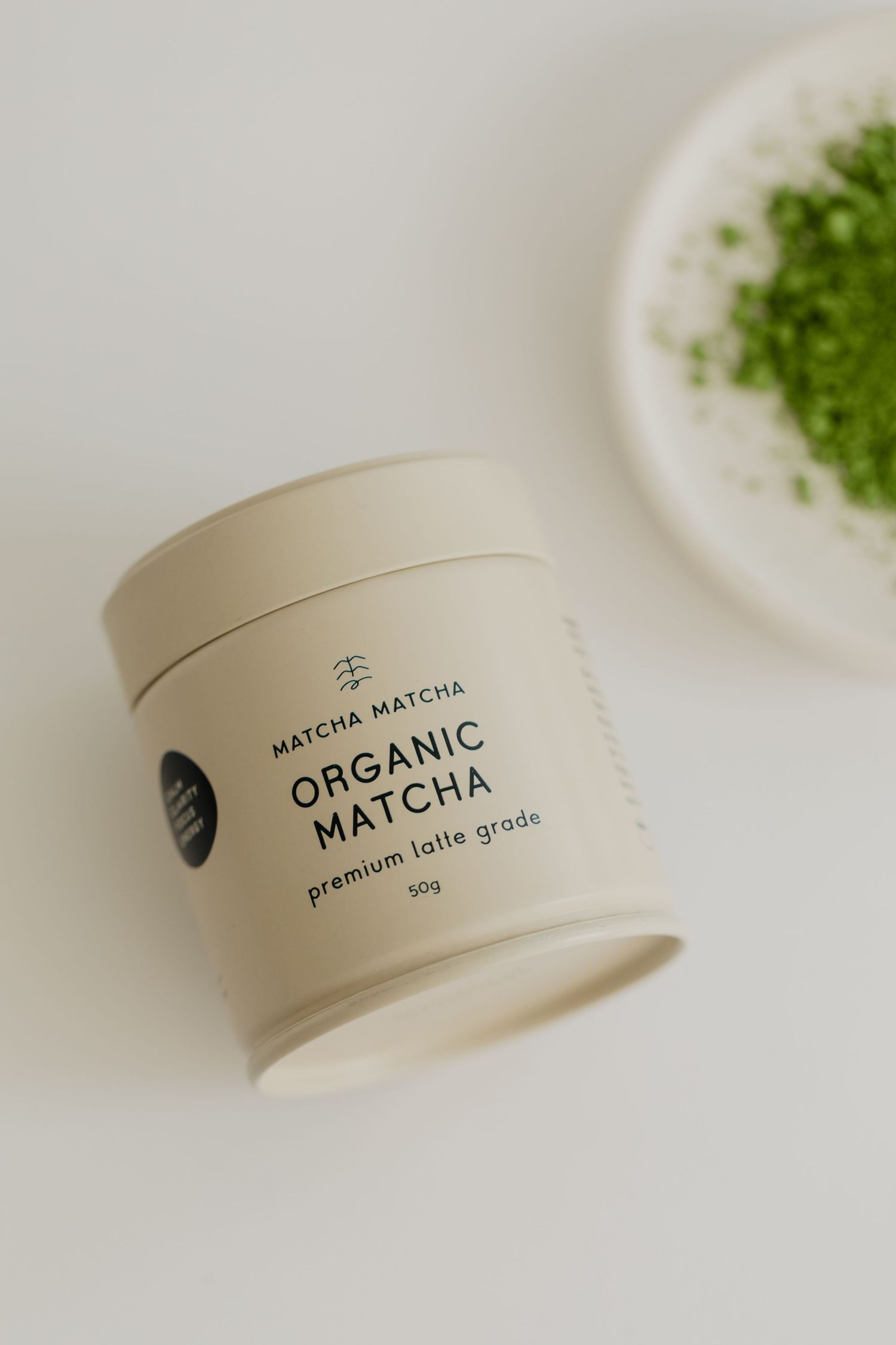 Close-up of organic matcha powder container with minimal white packaging design.