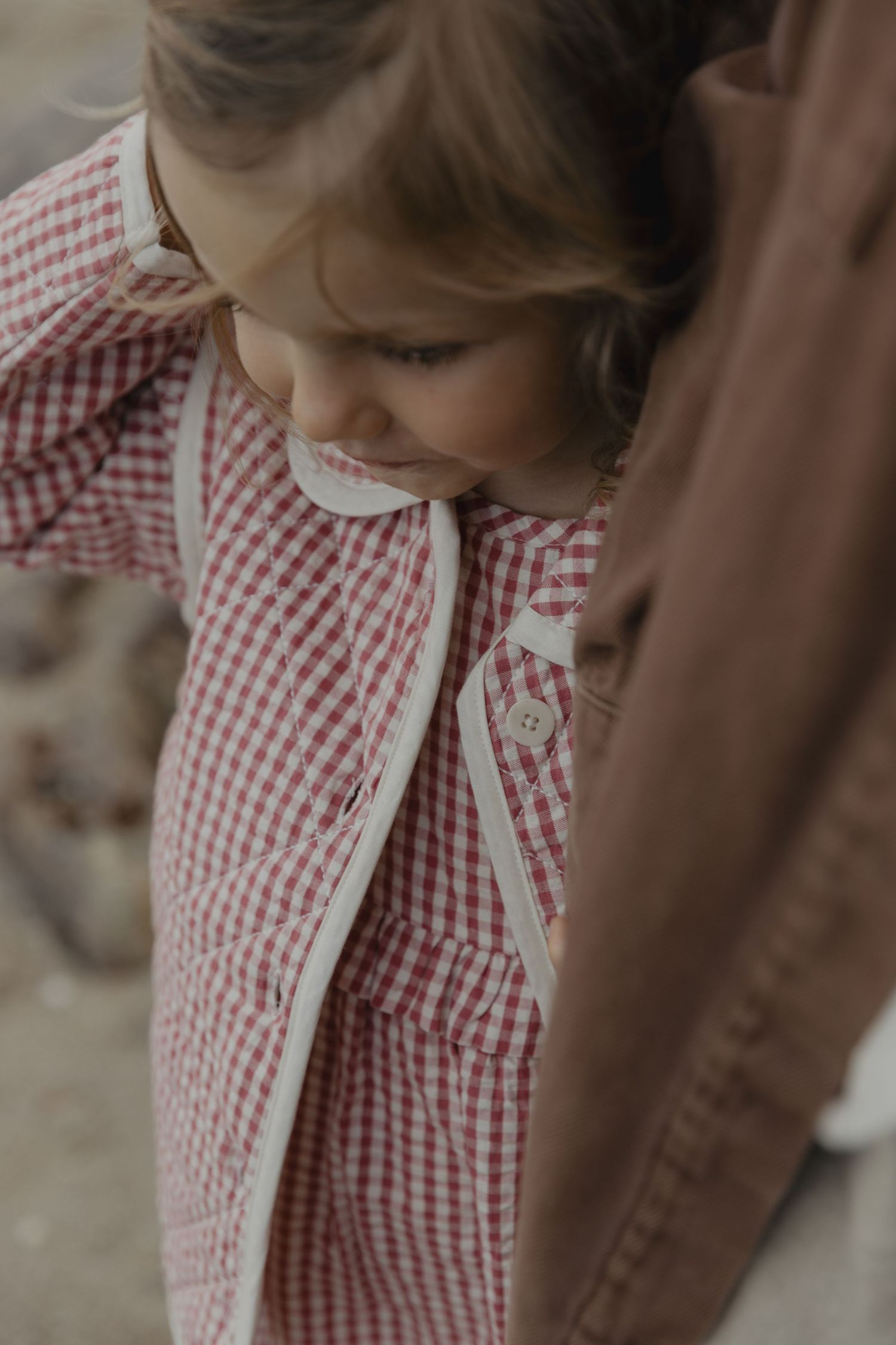 Close-up detail of a red and white gingham dress with delicate collar.