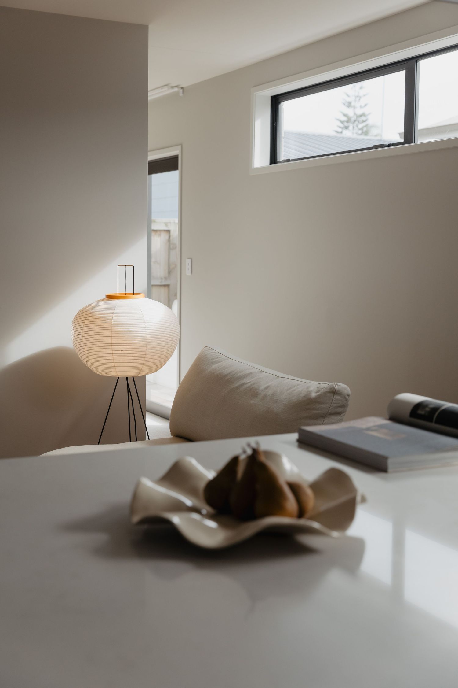 Minimalist room interior with paper lantern lamp and curved sculptural element.