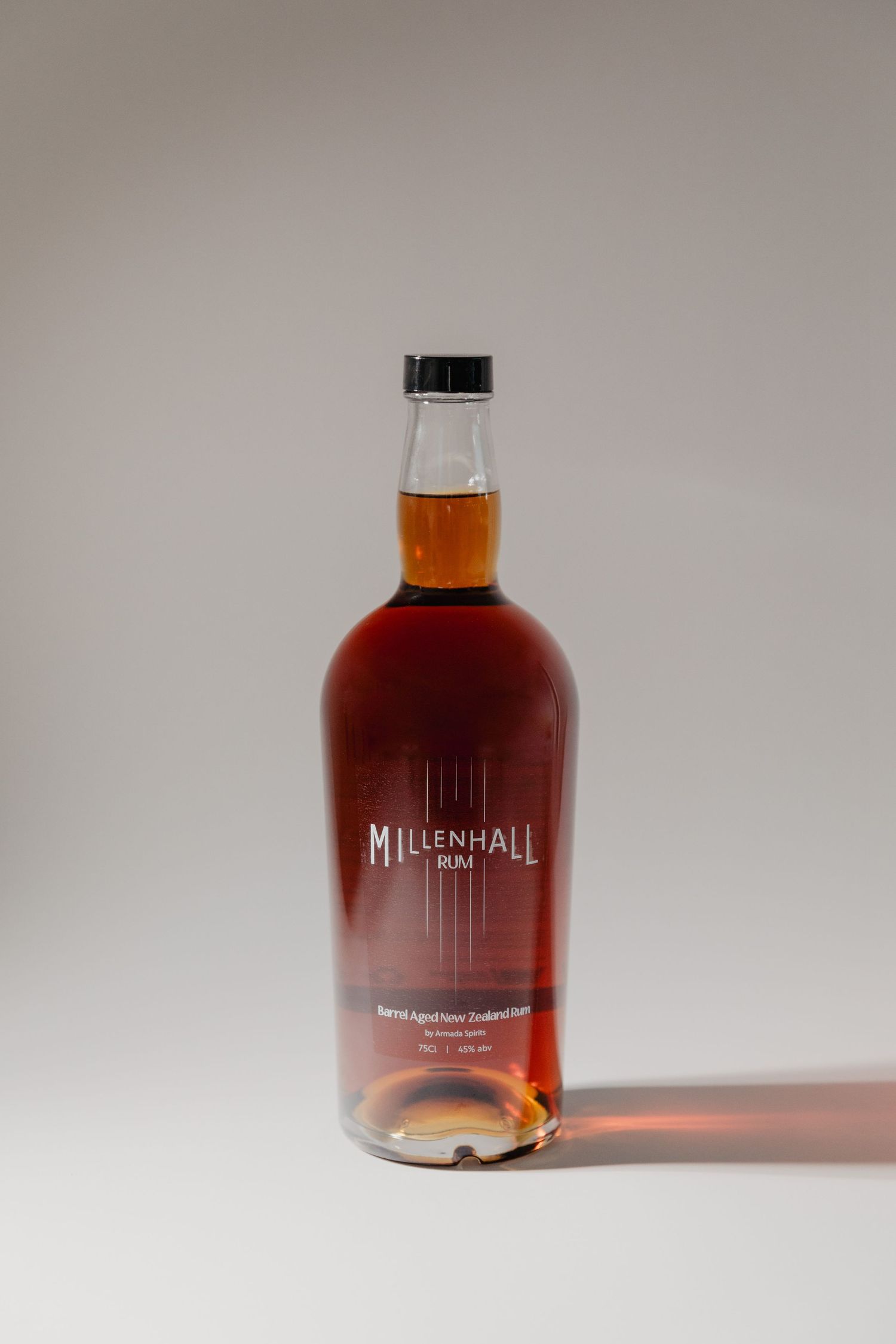 Bottle of Millenhall spirits against neutral background with dramatic lighting.