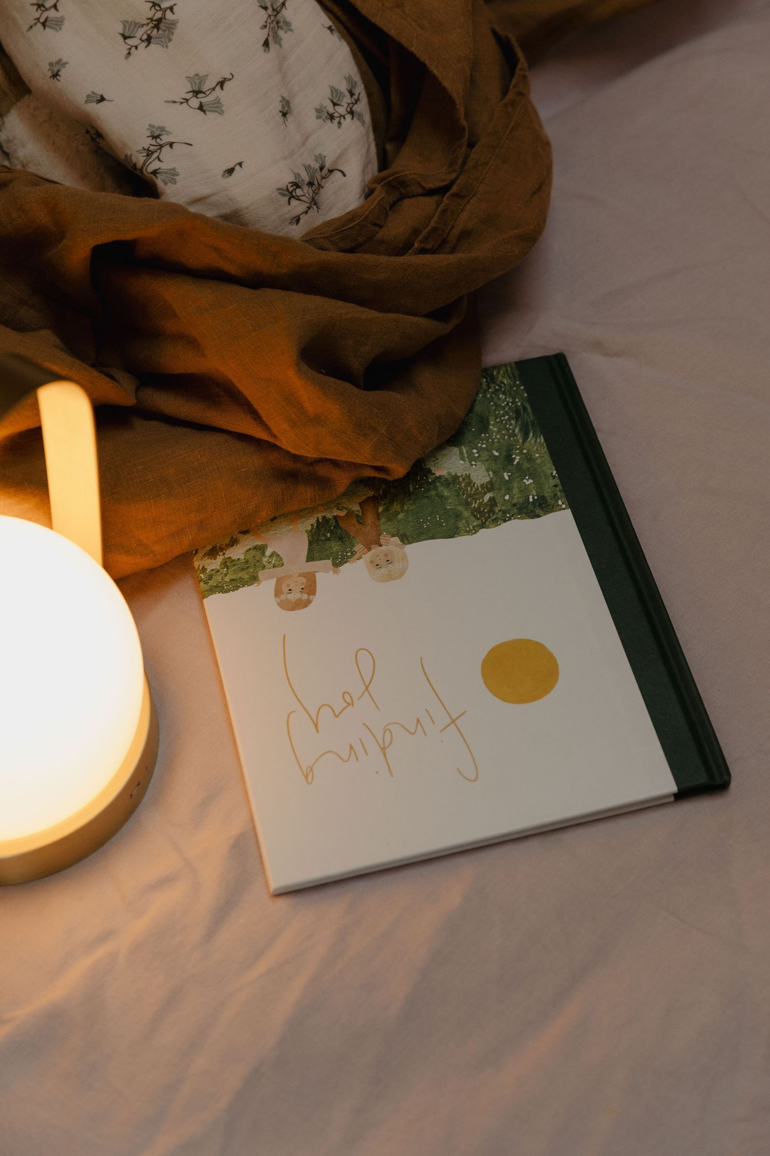 Warm-lit scene with cards or papers and a glowing lamp on a soft textile surface.