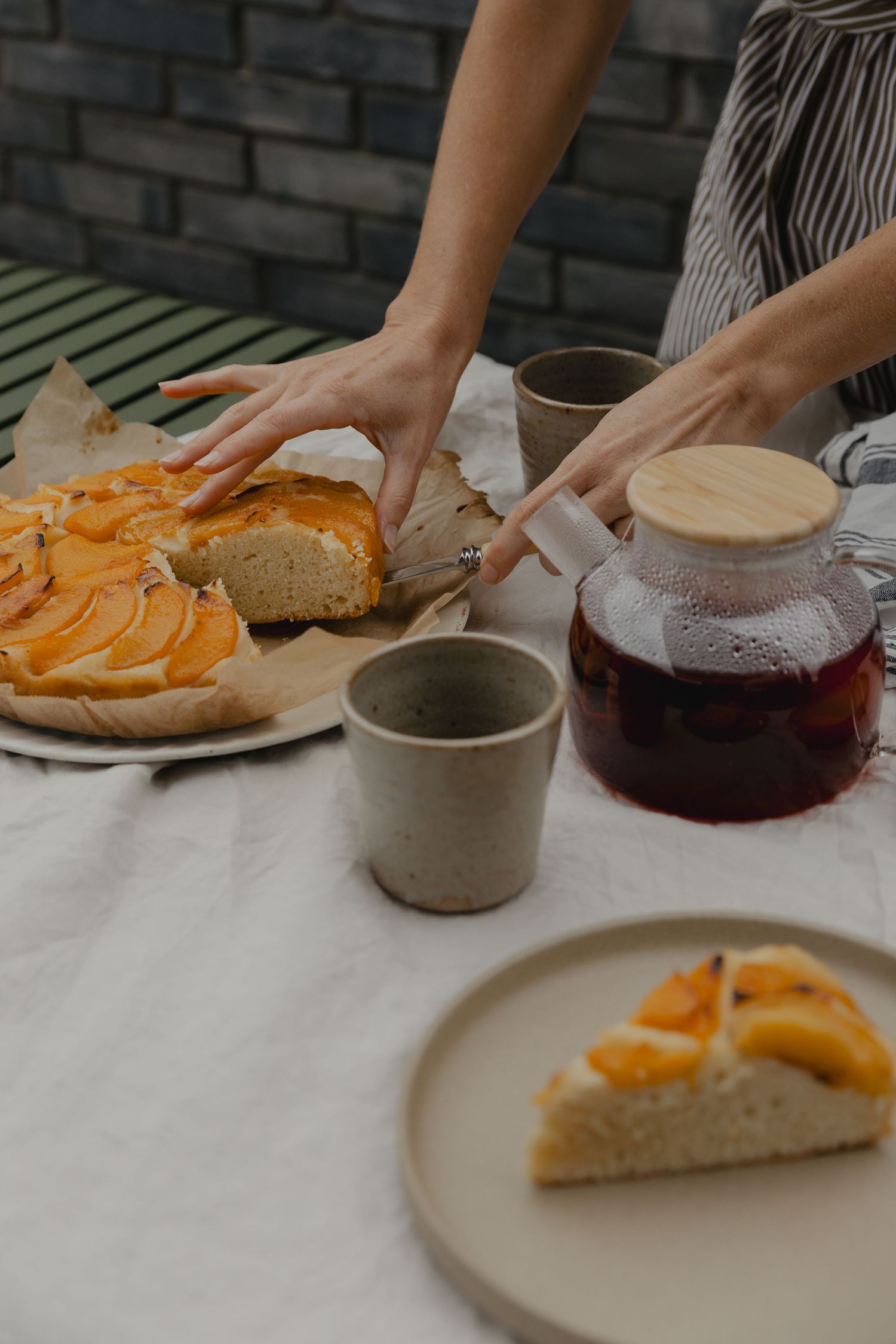 Orange slices arranged on a white surface next to ceramic cups and plates.