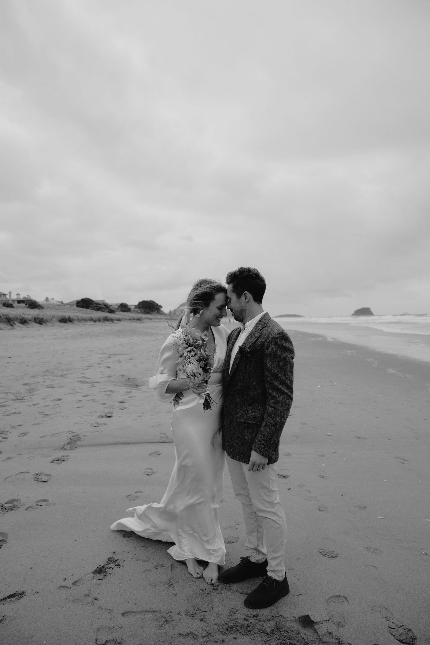 Romantic black and white photo of a couple dancing on a misty beach.