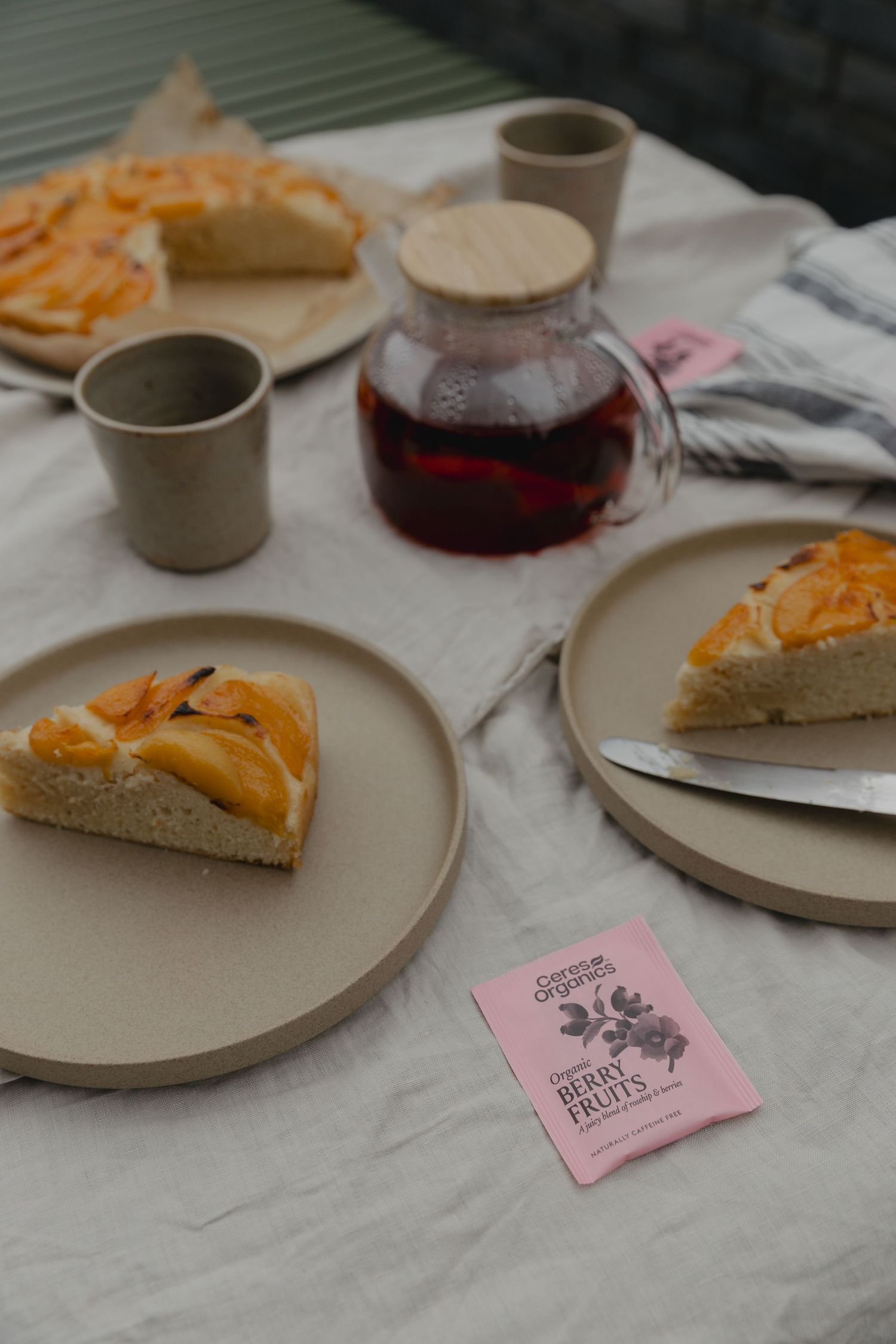 Tea service with pastries and ceramic plates on white linen tablecloth.