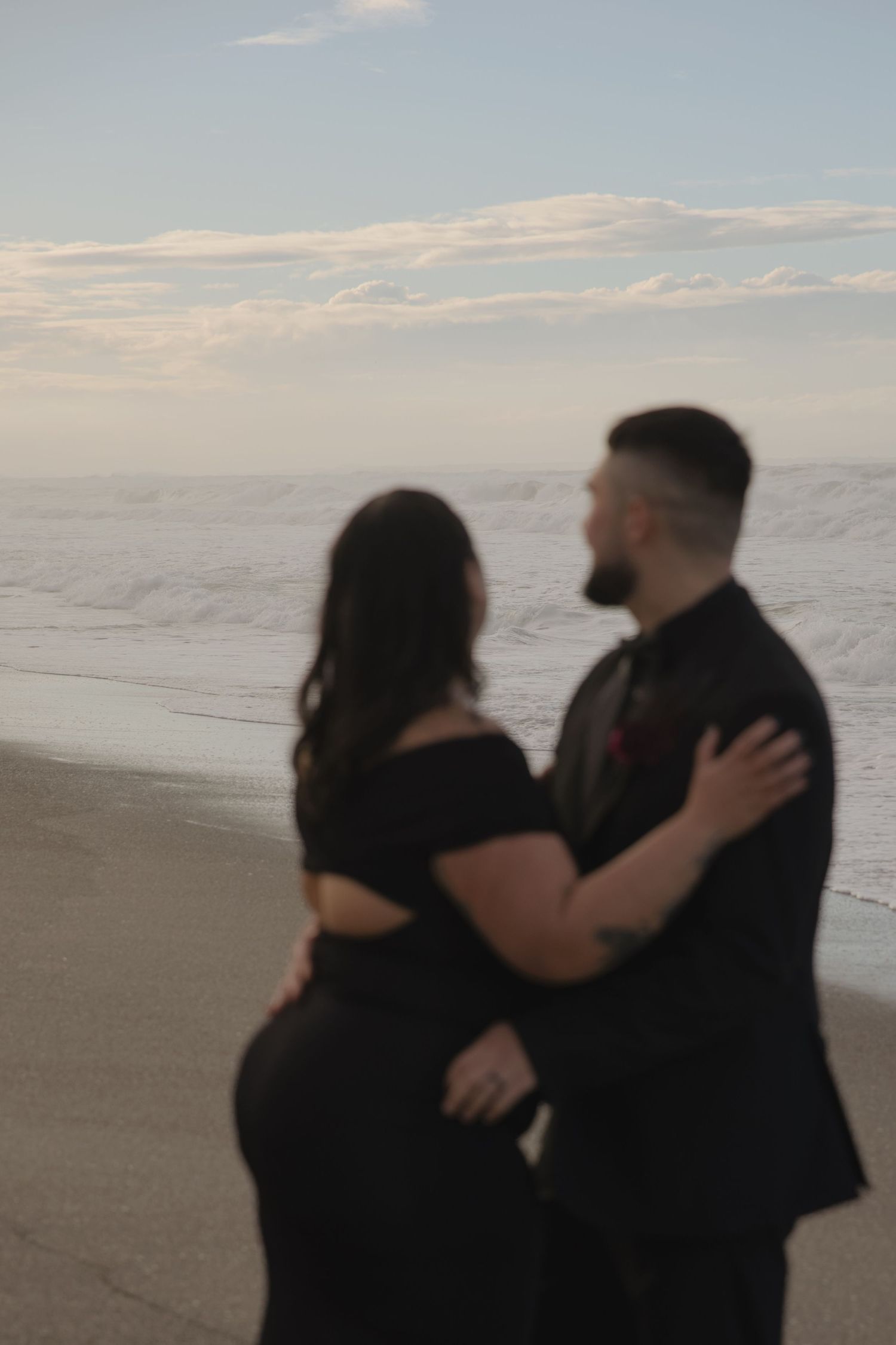 Silhouetted couple embracing on beach at sunset.
